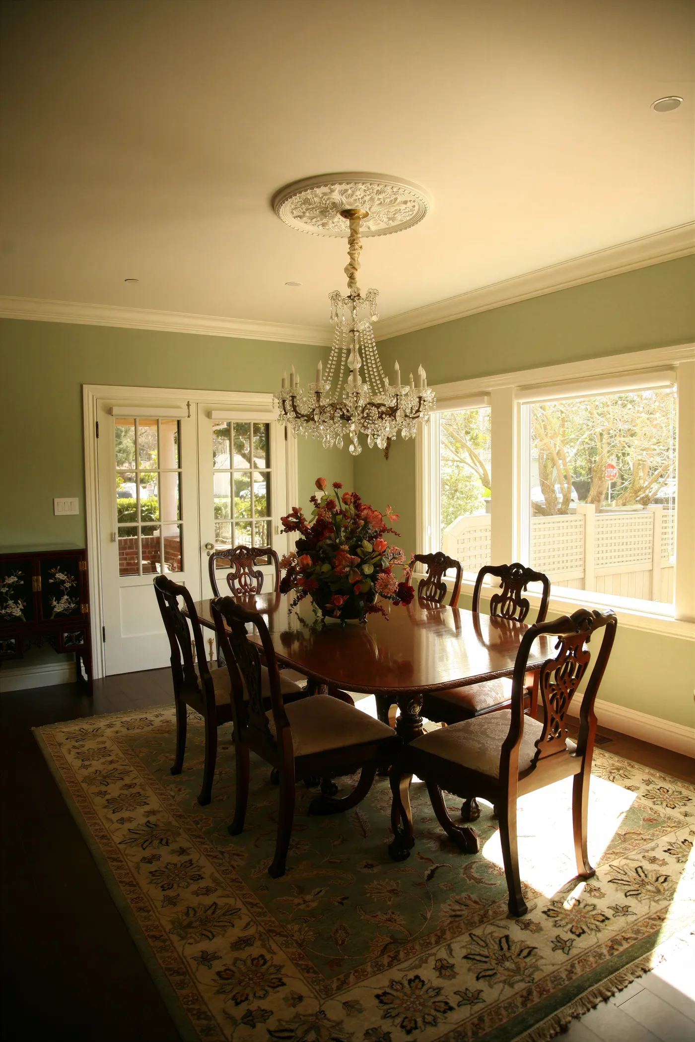 Dining room in sage green with a crystal chandelier over the table