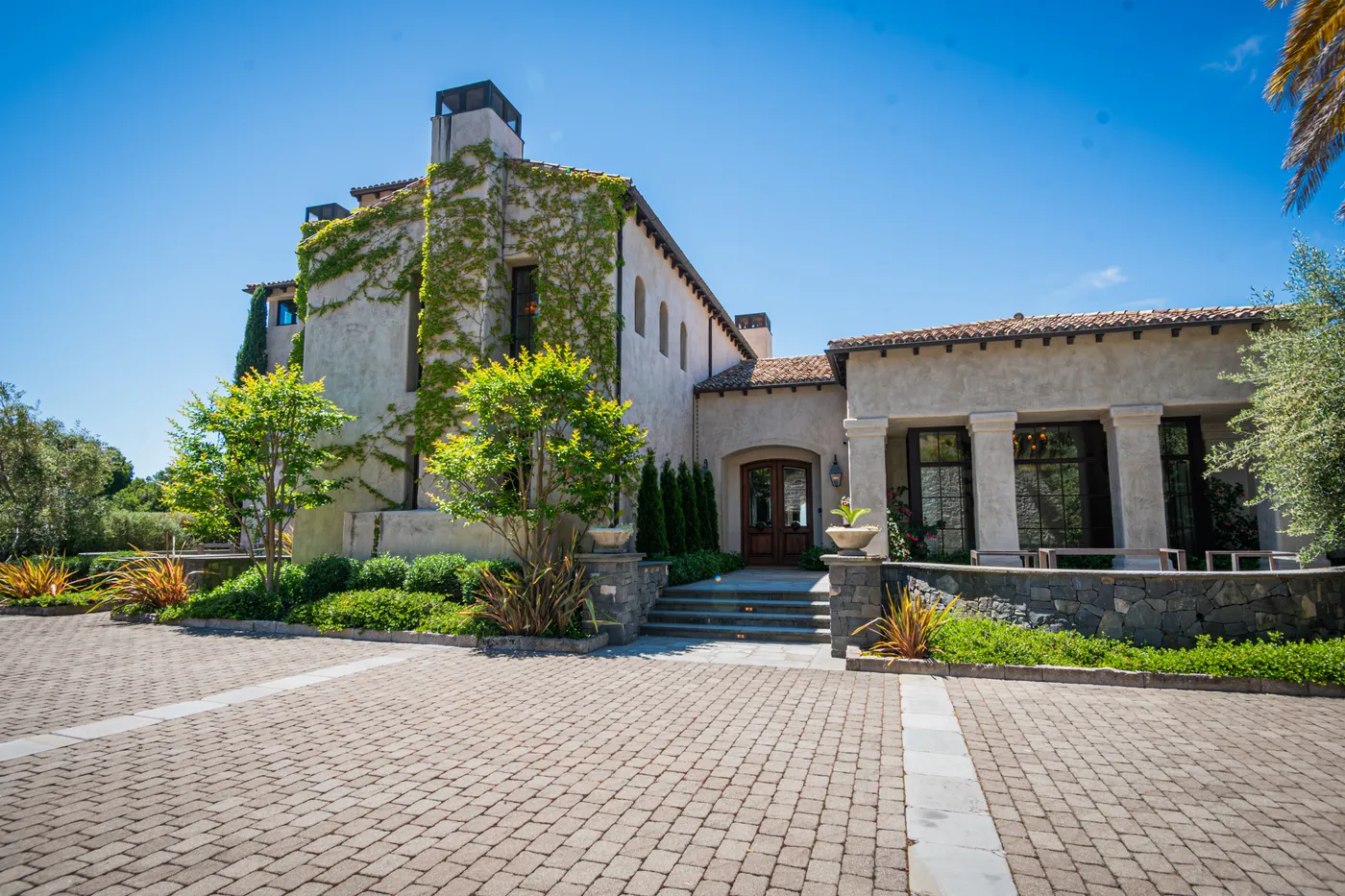 The stucco house from the paver motor court, ivy climbing the tower wall