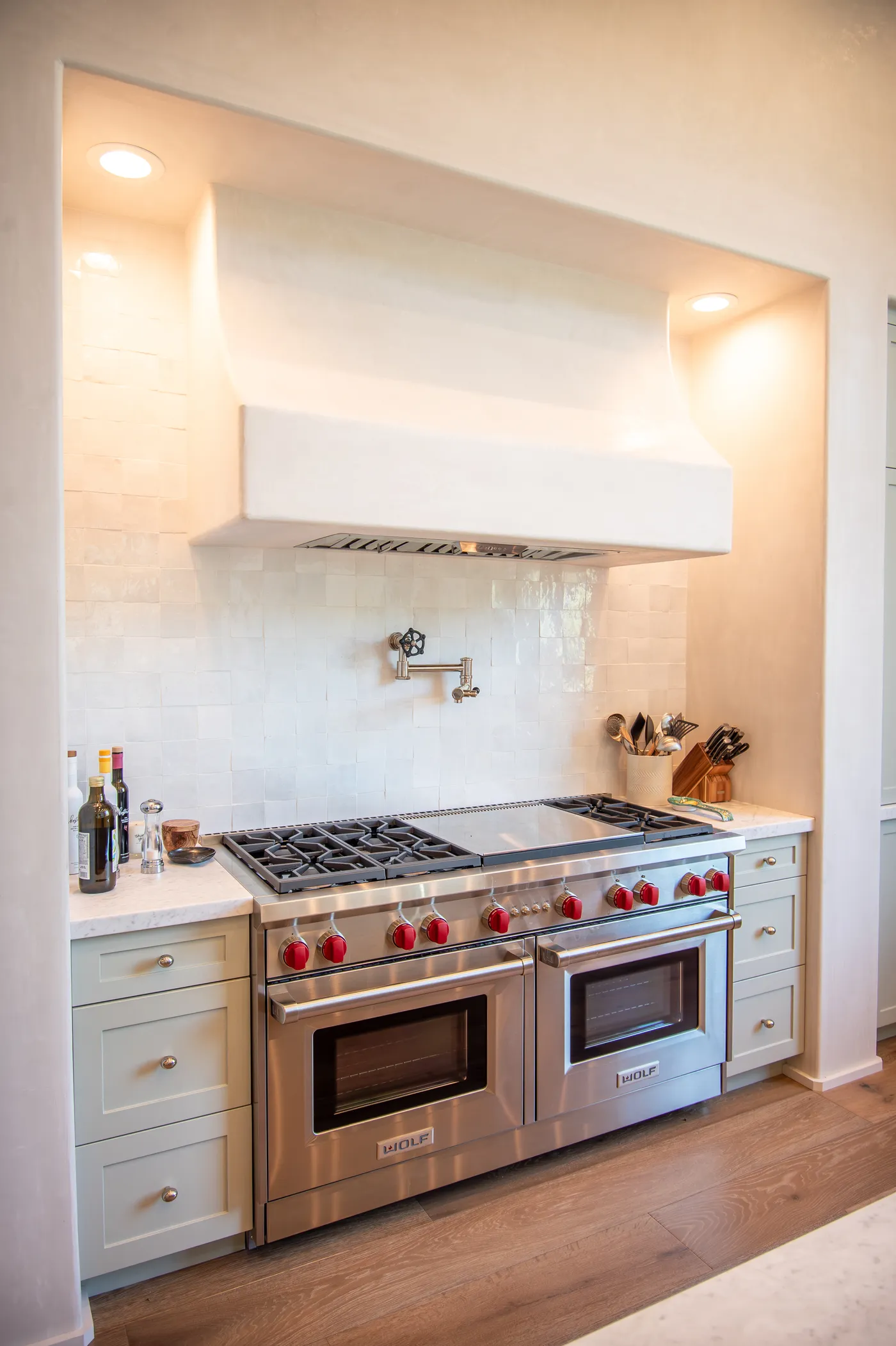 Range wall with a plaster hood, pot filler and glazed tile backsplash