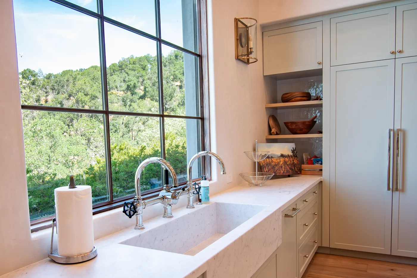 Scullery with a marble sink and twin faucets below a tall steel window