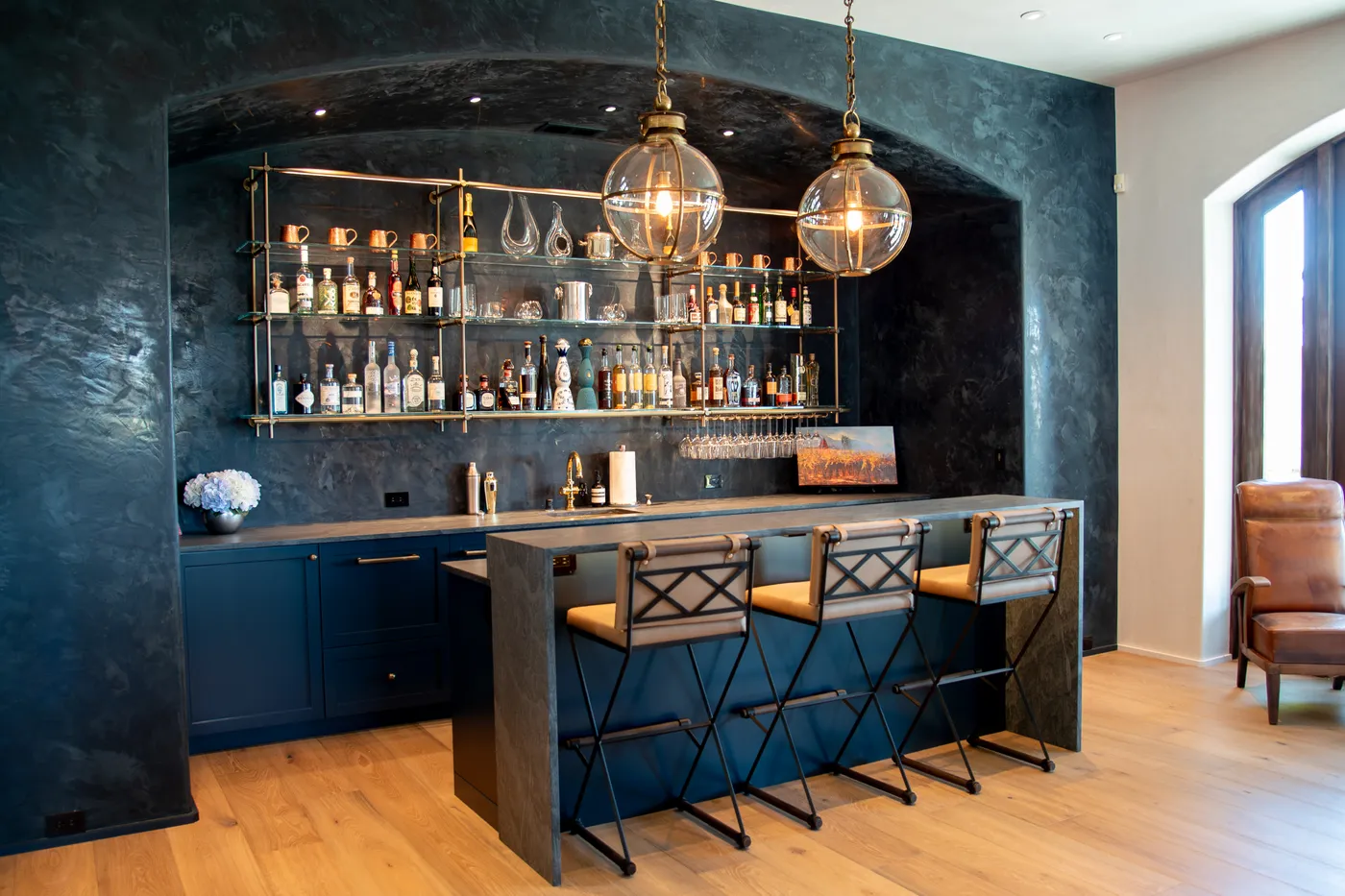 The rebuilt bar in a dark plaster alcove, with brass back-bar shelving and counter seating