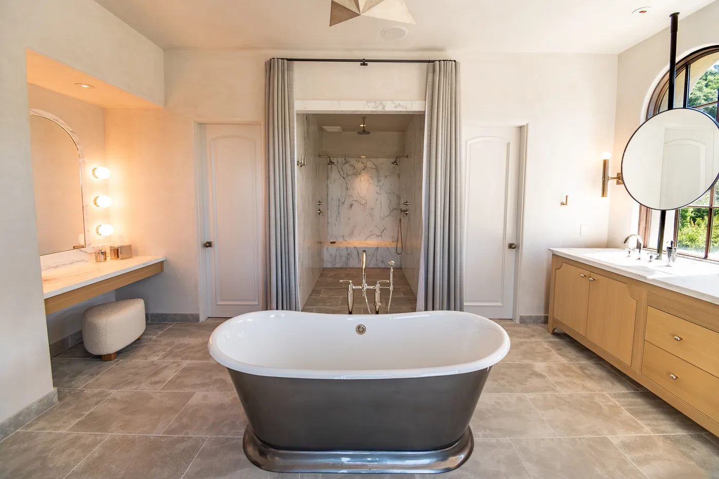 The primary bath from the dressing side, with a lit makeup counter and the shower beyond
