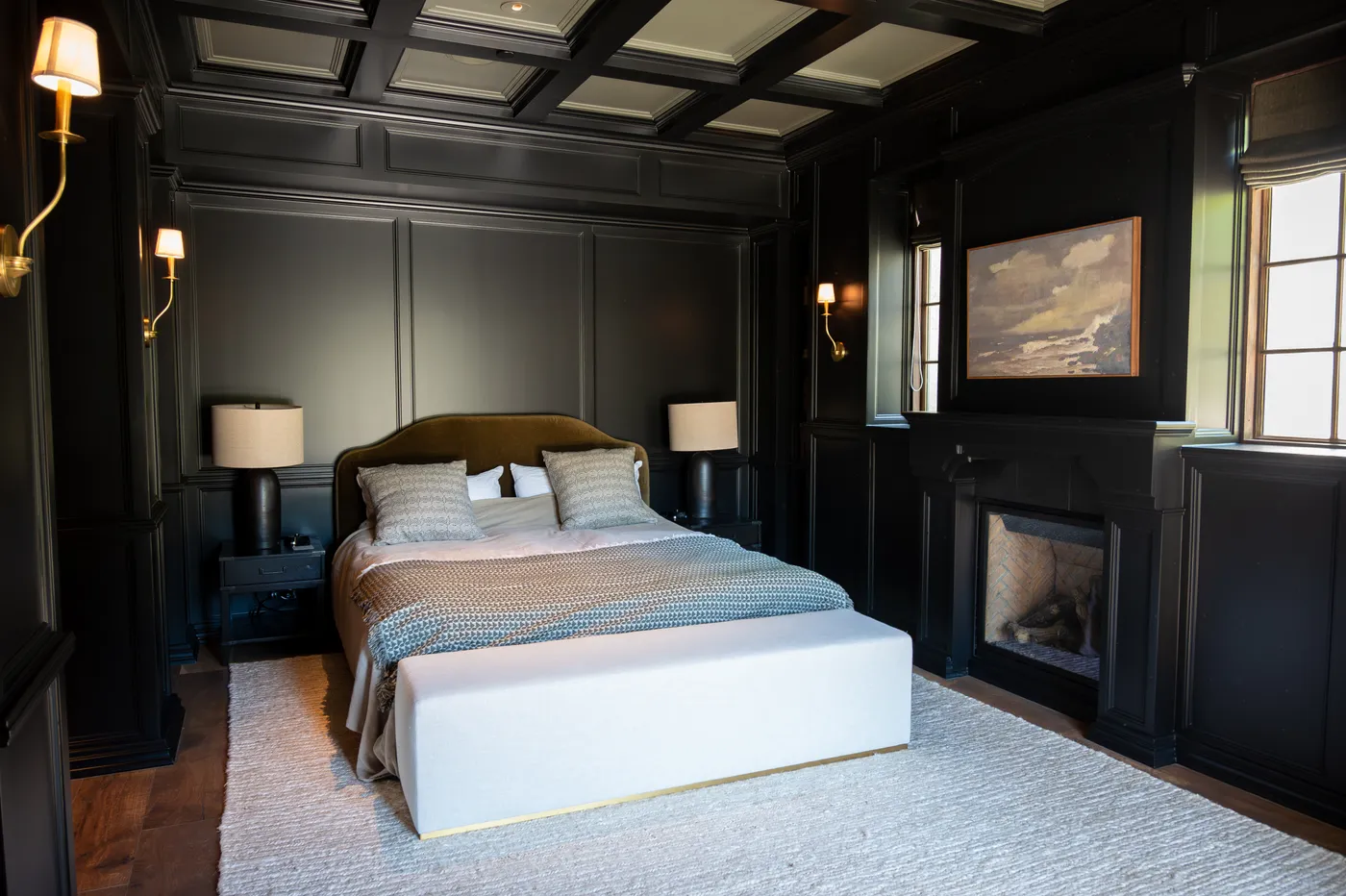 Bedroom panelled in near-black with a coffered ceiling and a fireplace