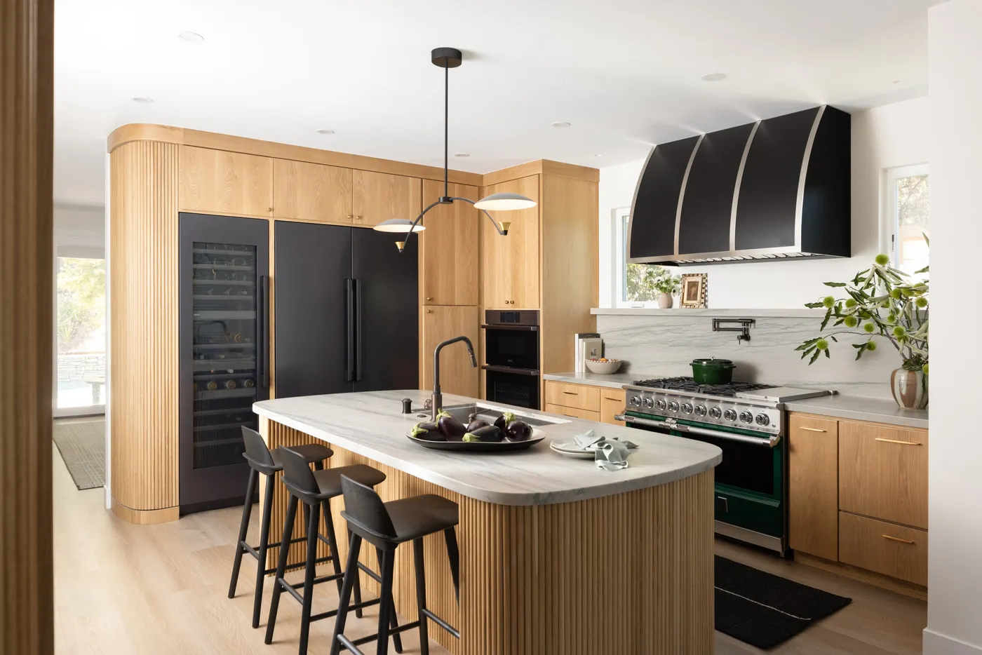 The rebuilt kitchen with a marble island, range and counter seating