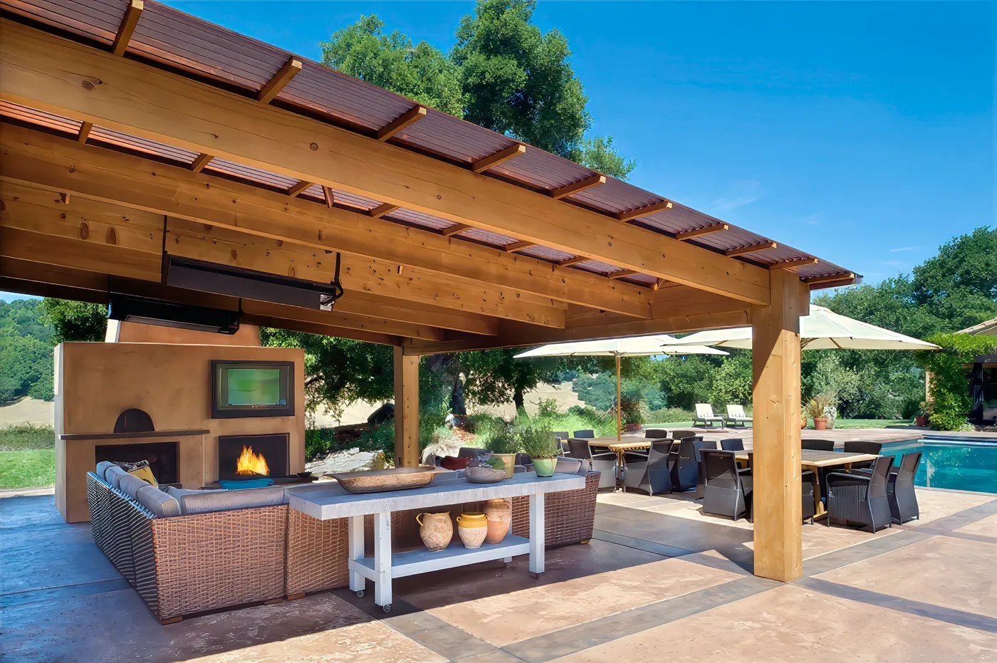 The covered outdoor room with its plaster fireplace and dining table, open to the pool