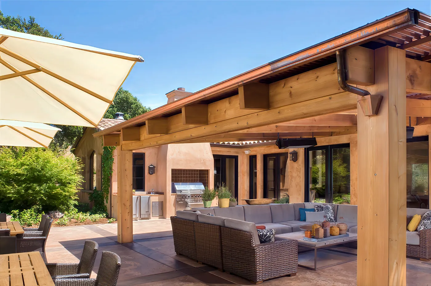 Outdoor kitchen and grill beside the sectional, under the timber roof