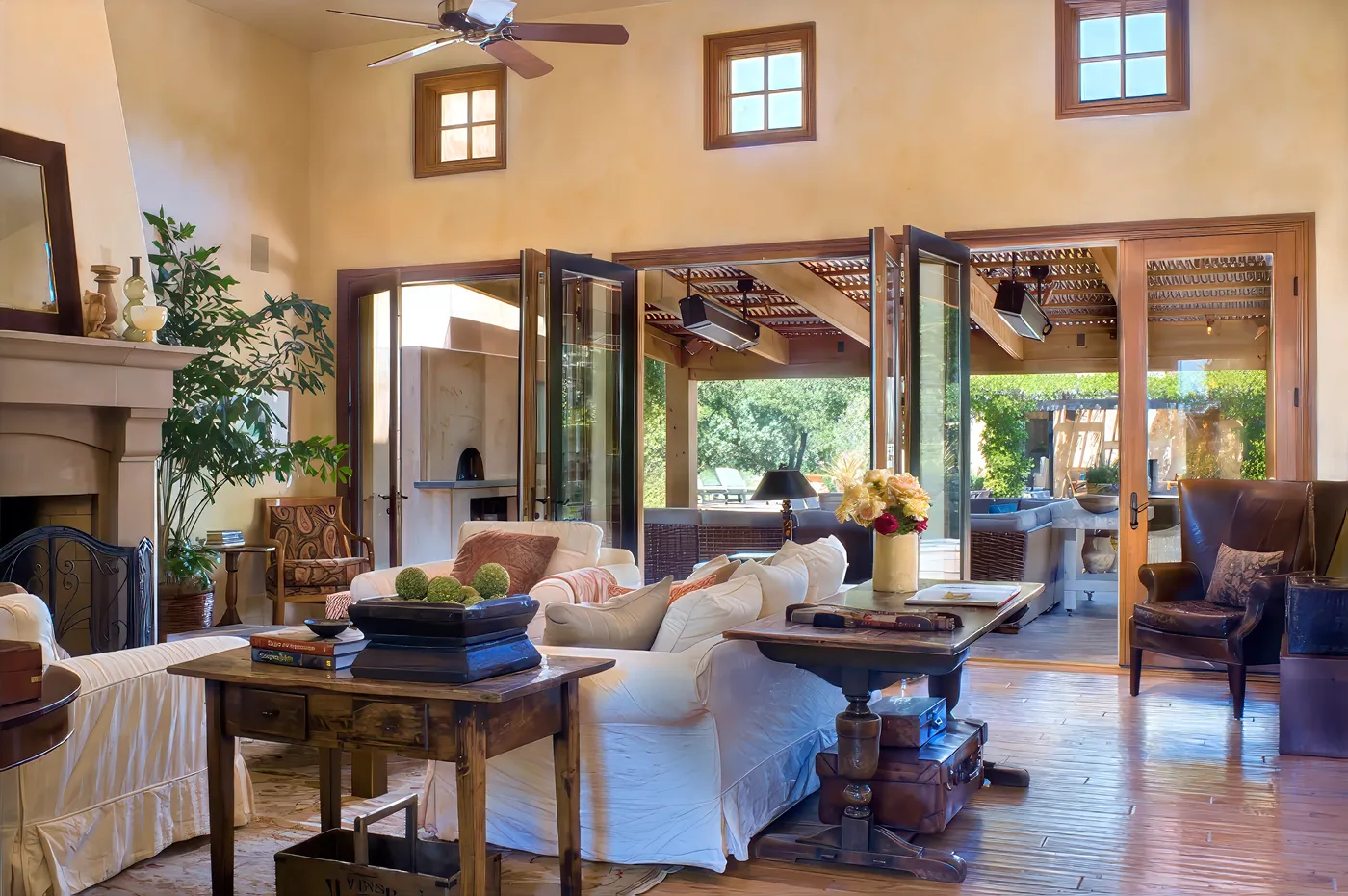 Living room with a plaster fireplace, folding glass doors open to the covered patio