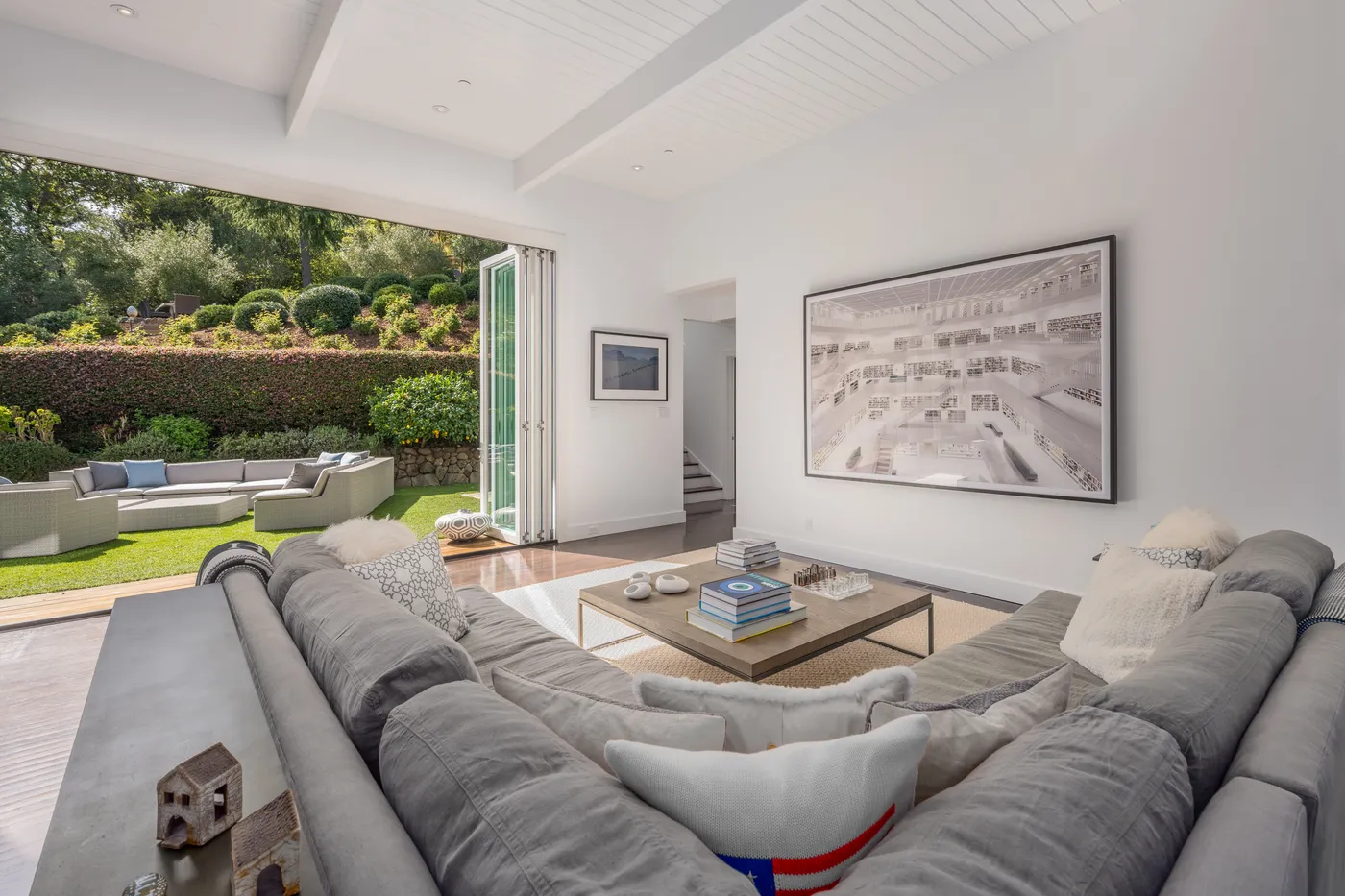 Living room with folding glass doors open to the hedged garden