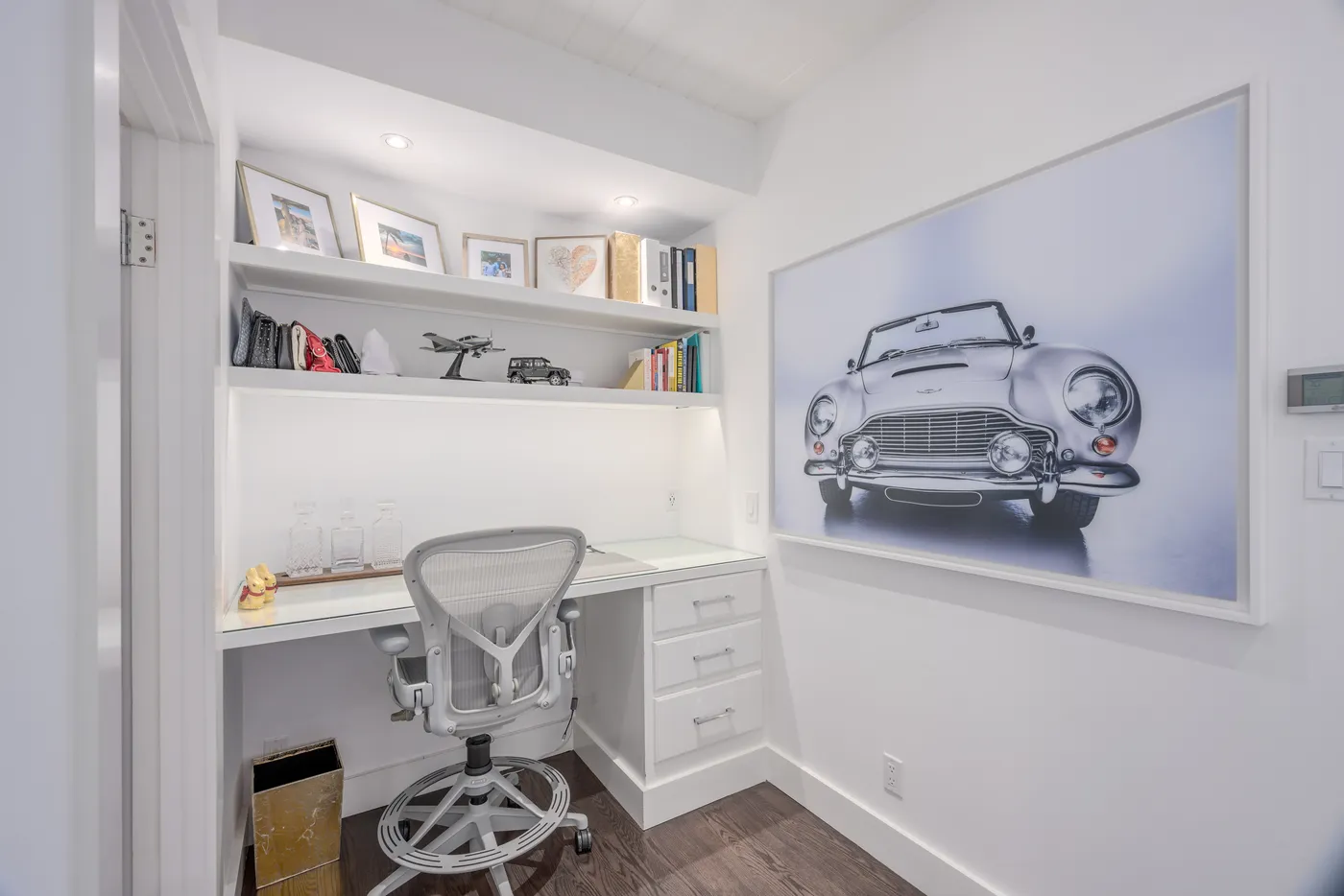 Study nook with a built-in desk below a classic car photograph