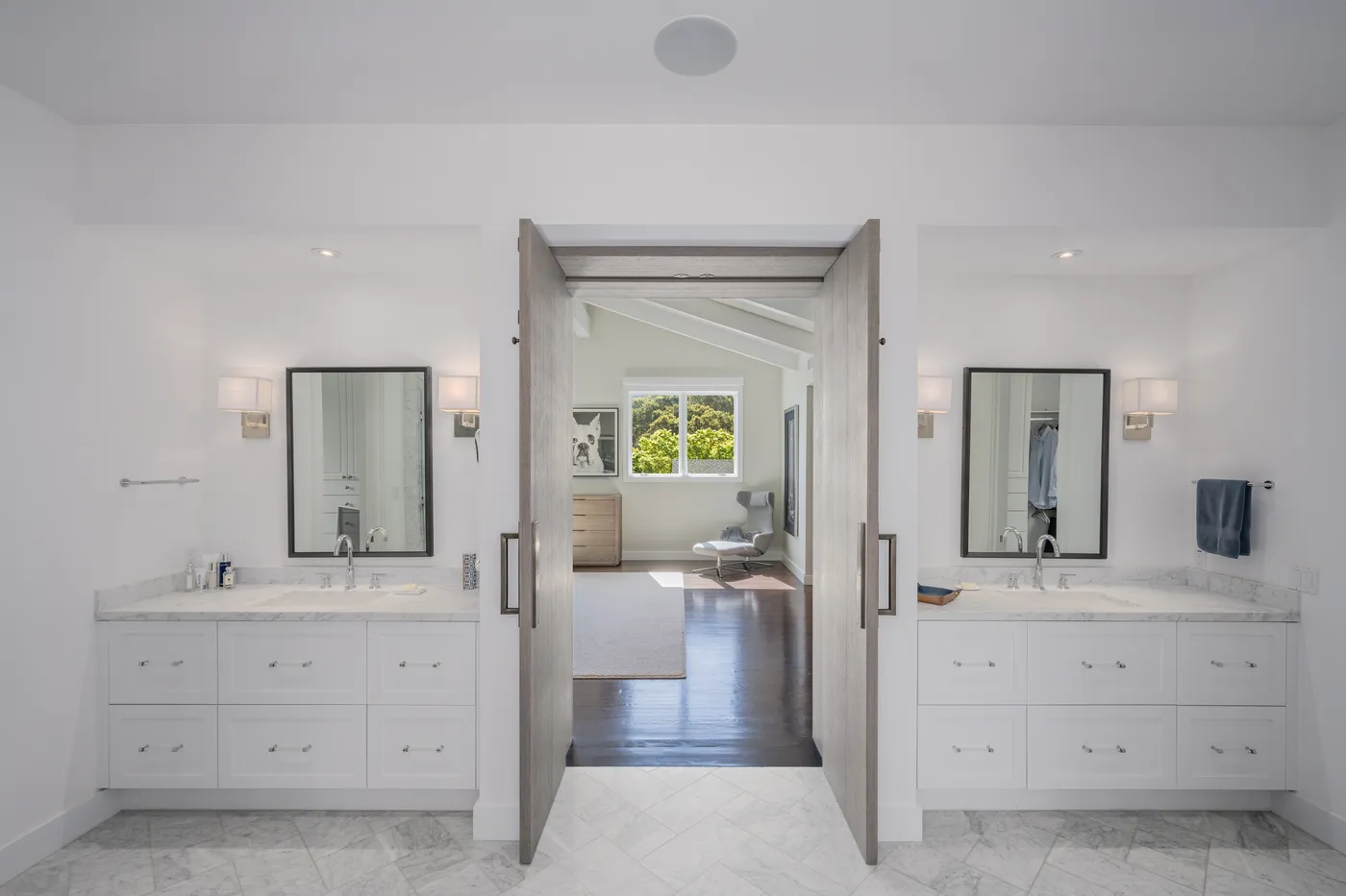 Bathroom with a double vanity and paired mirrors, open to the bedroom