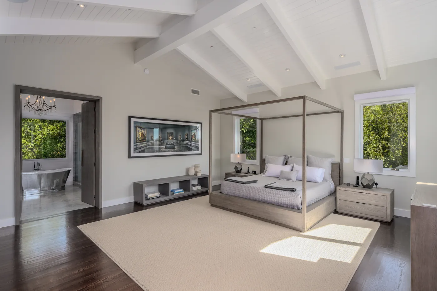 Bedroom with a canopy bed and a dresser under open beams