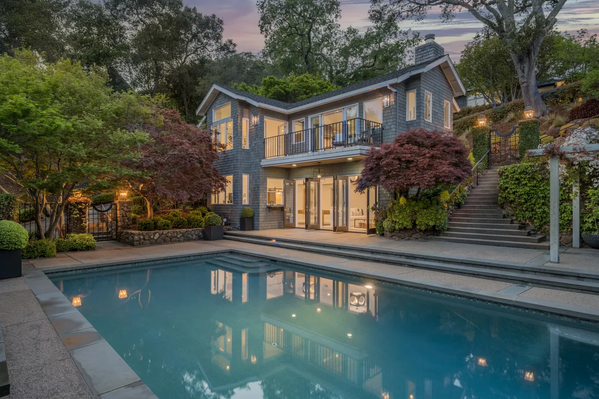 The remodeled house at dusk, lit above the lap pool and its terraced gardens
