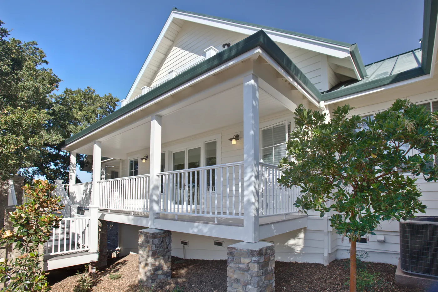 Corner of the covered porch, white railings and columns on stone piers