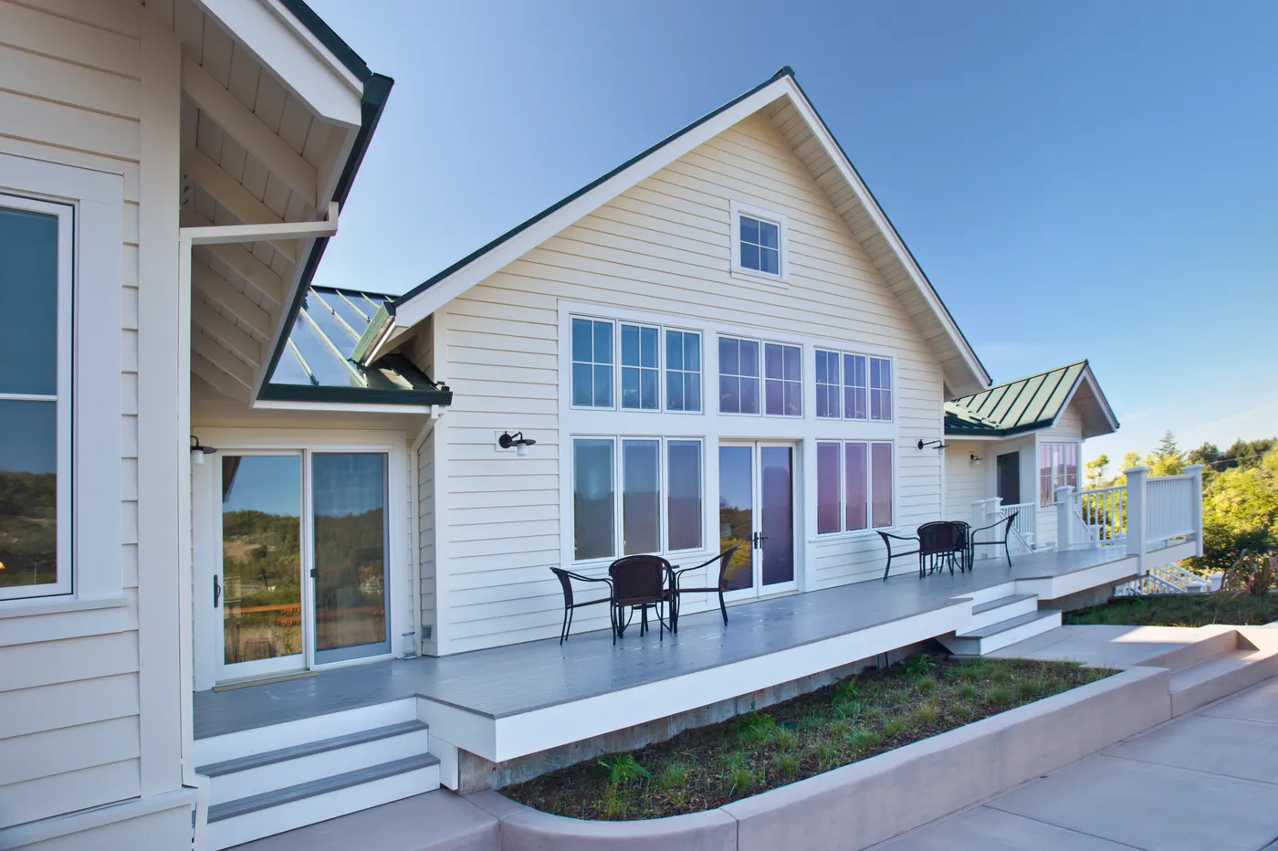 Rear porch with square columns and tall windows under a green metal roof