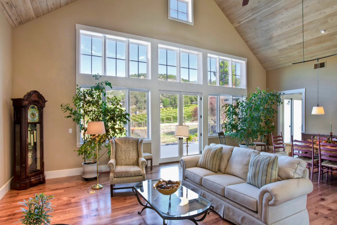 Living room under a vaulted plank ceiling with a wall of windows to the hills