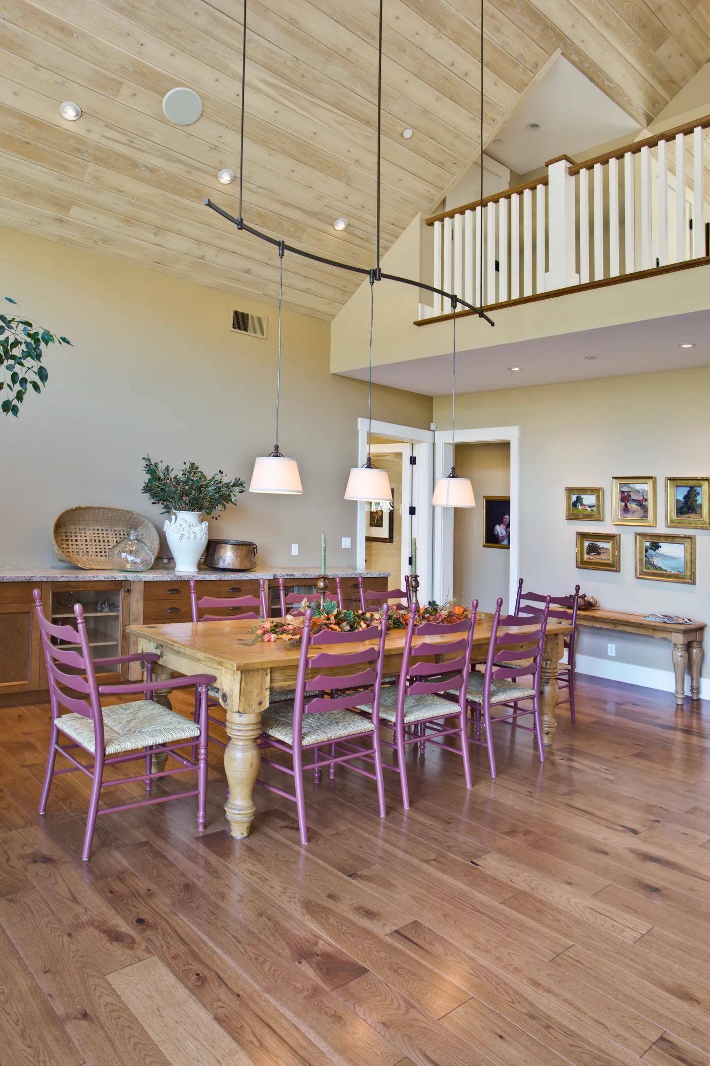 Long farmhouse dining table under pendant lights and a plank ceiling