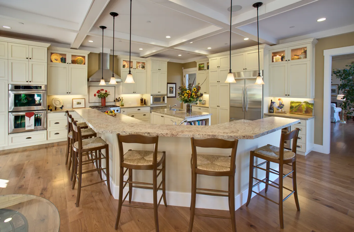 Kitchen with a curved granite island, counter stools and a coffered ceiling
