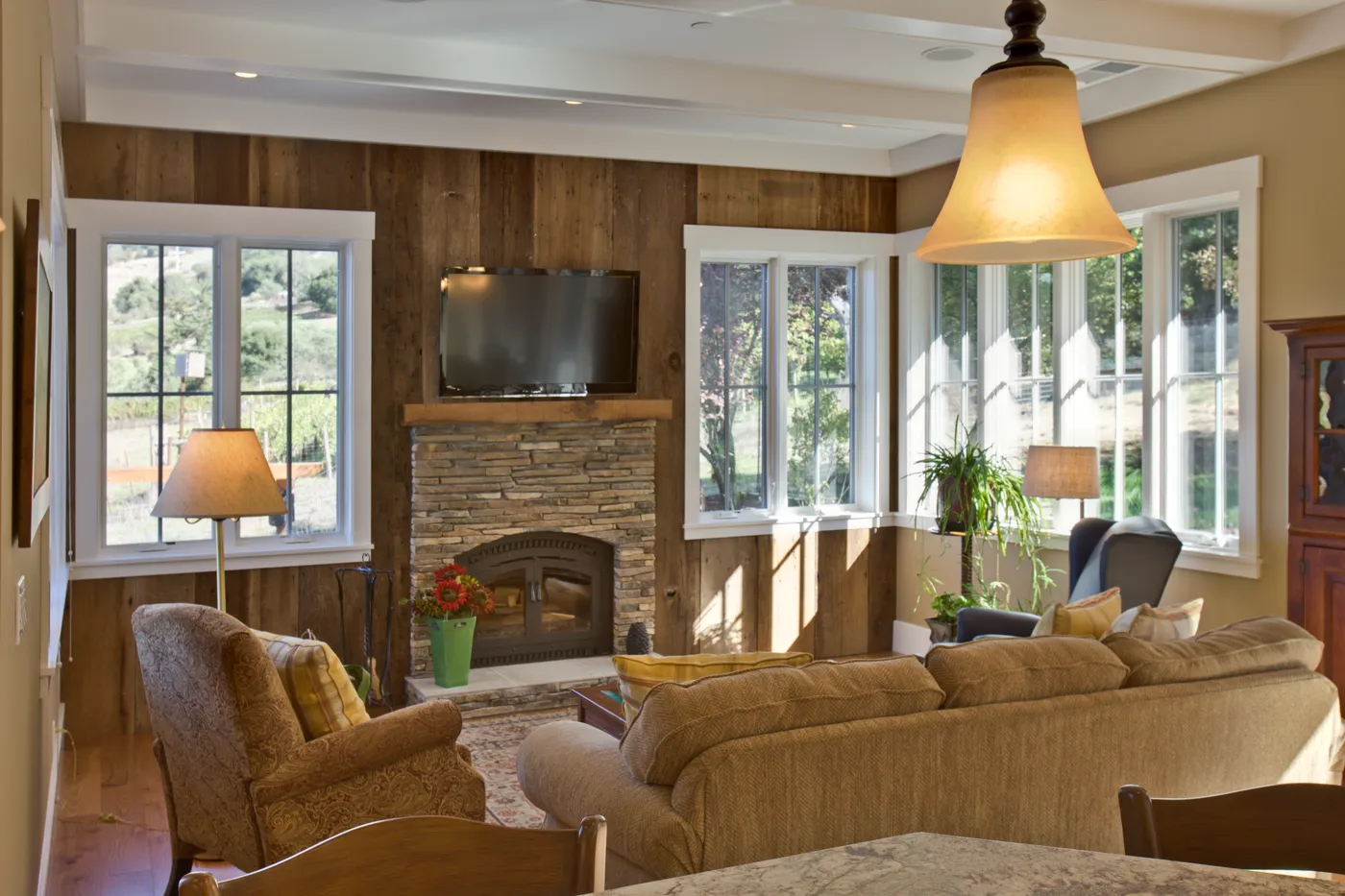 Family room with a stone fireplace set into a reclaimed timber wall