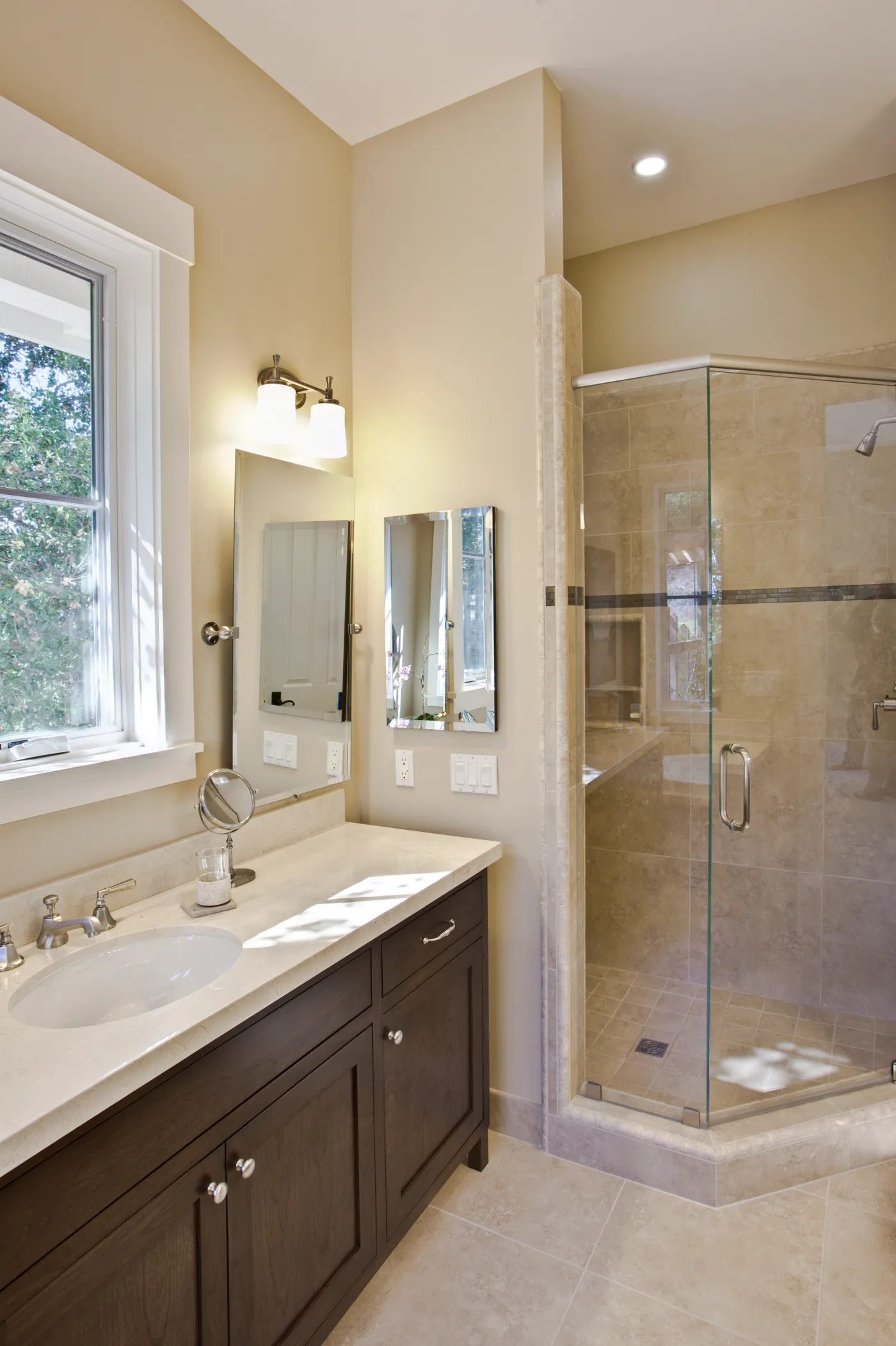 Bath with a travertine corner shower beside a timber vanity