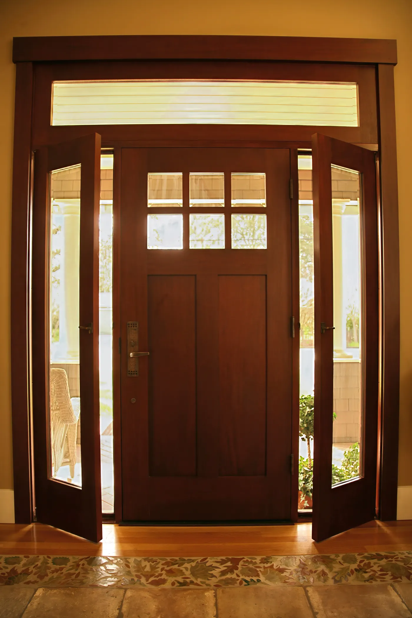 Mahogany front door with a divided-light transom and sidelights standing open