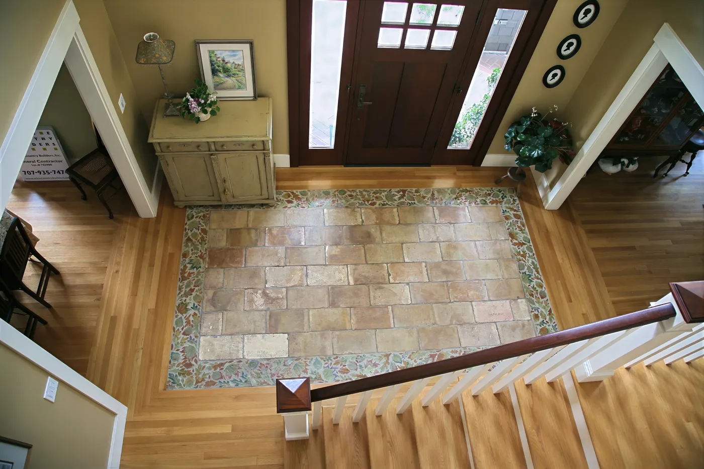 Entry hall seen from the stair landing, a stone floor inlaid in the oak boards