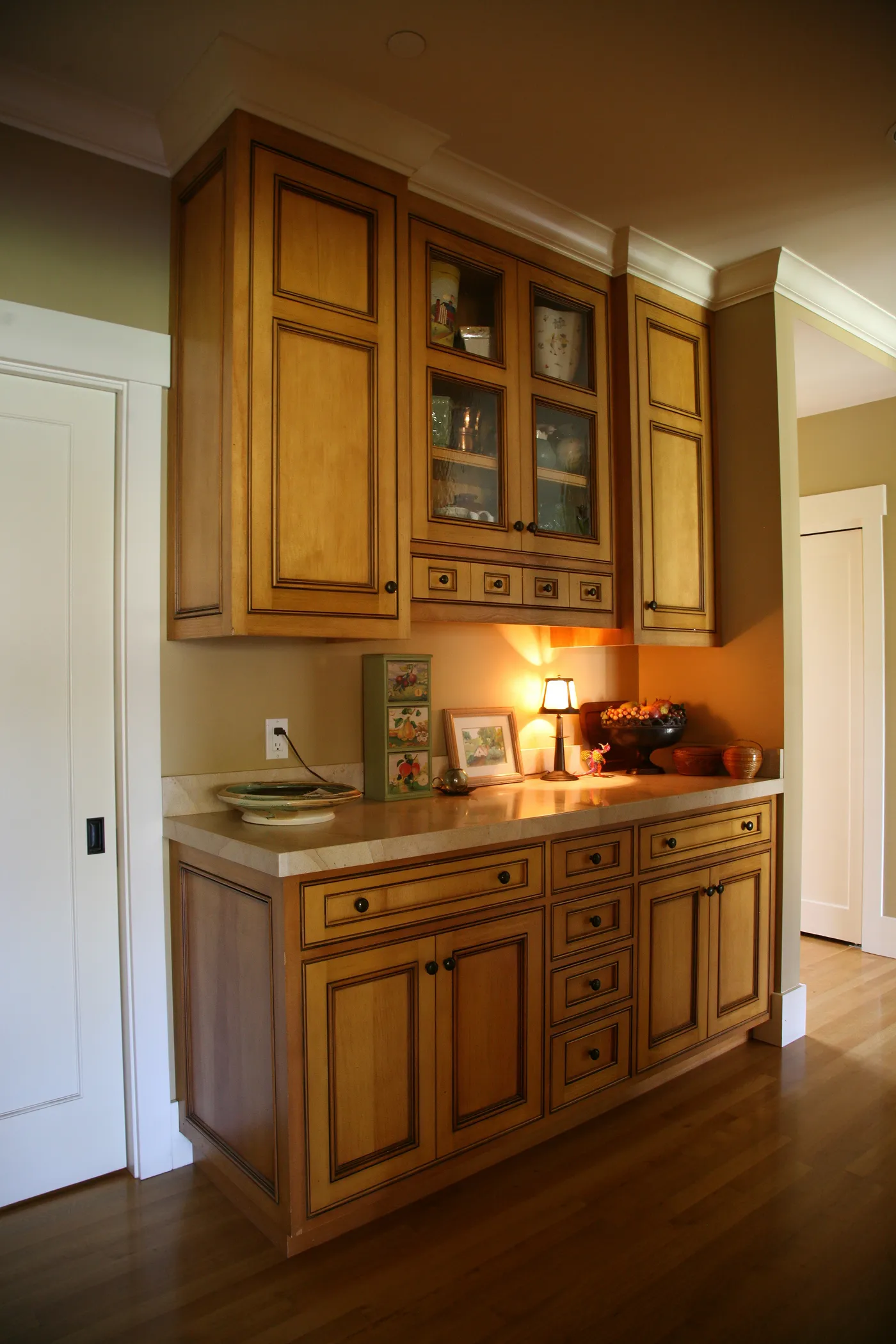 Serving cabinet with glazed uppers and drawers set into the hallway wall