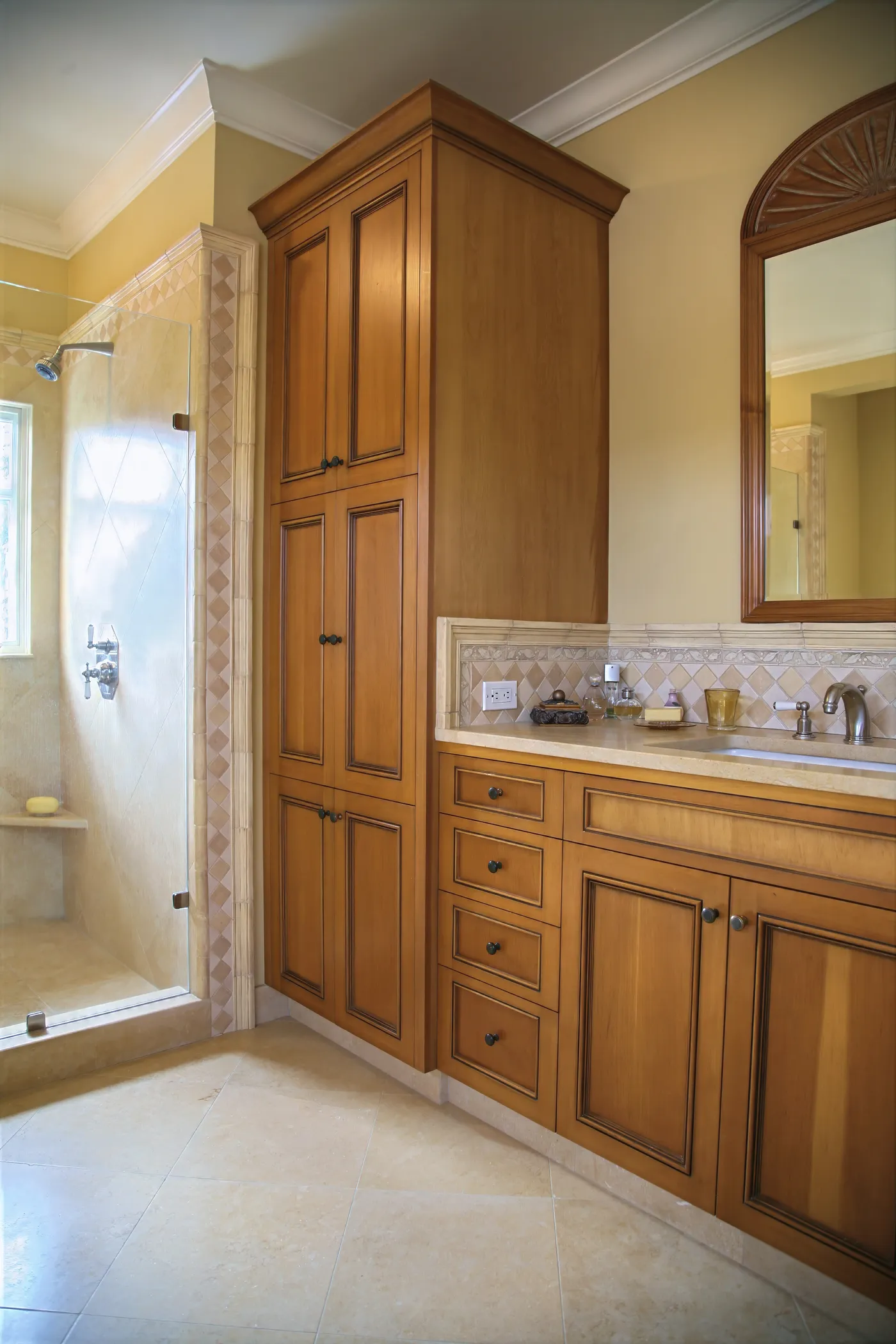 Bathroom with a full-height linen cabinet beside a tiled walk-in shower