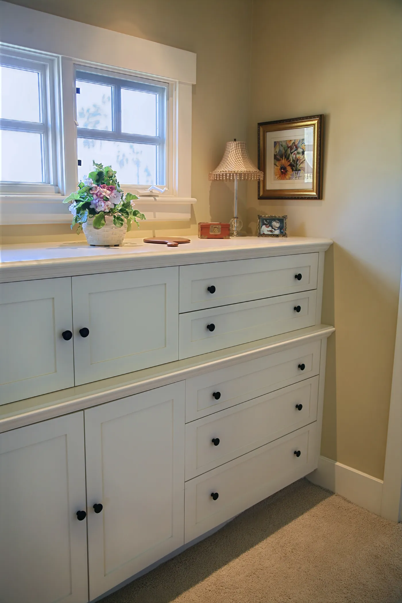 Built-in painted dresser and cabinets under a window in a bedroom