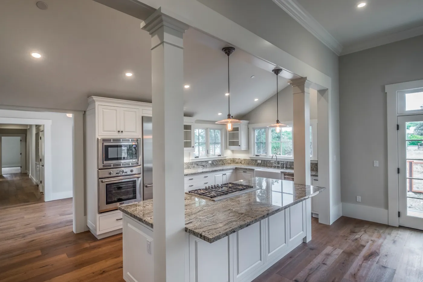 The kitchen seen from the living side, past square columns to the vaulted ceiling