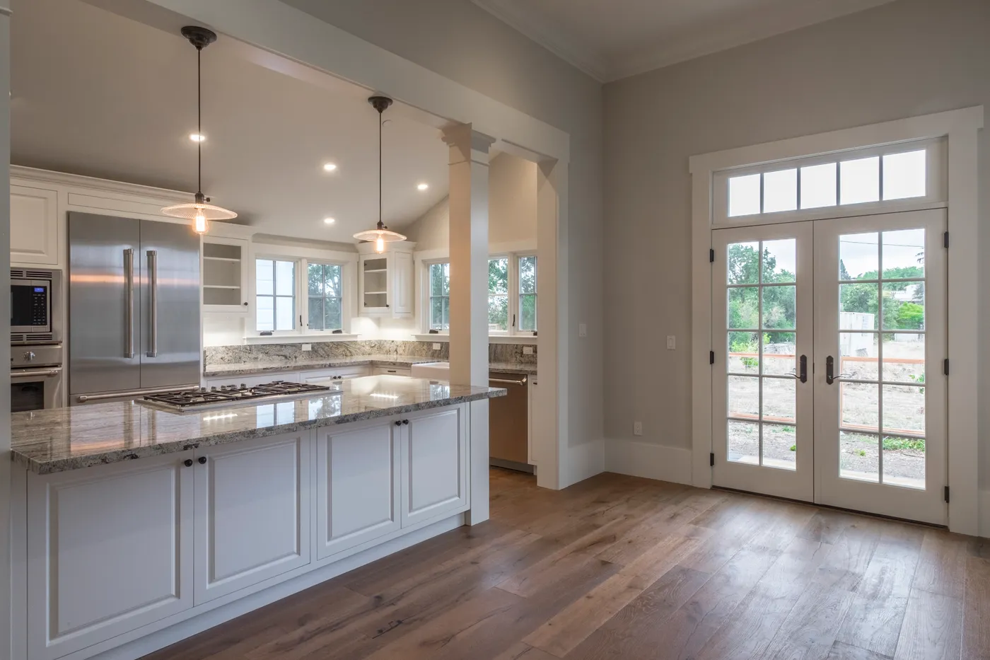 Kitchen island with a gas cooktop, French doors to the porch beyond