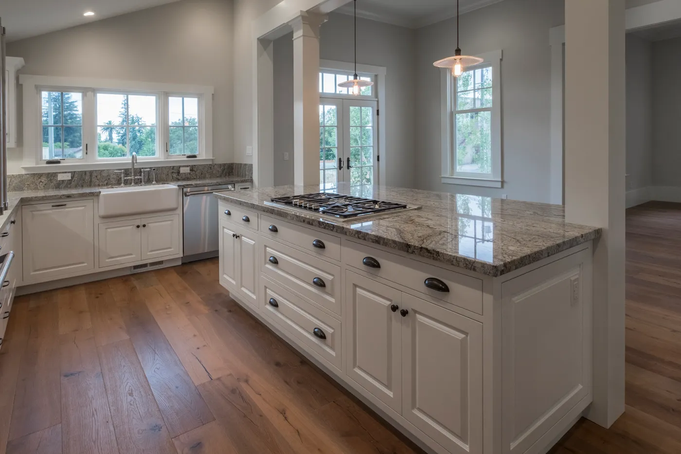 Granite-topped island with the farmhouse sink and windows behind