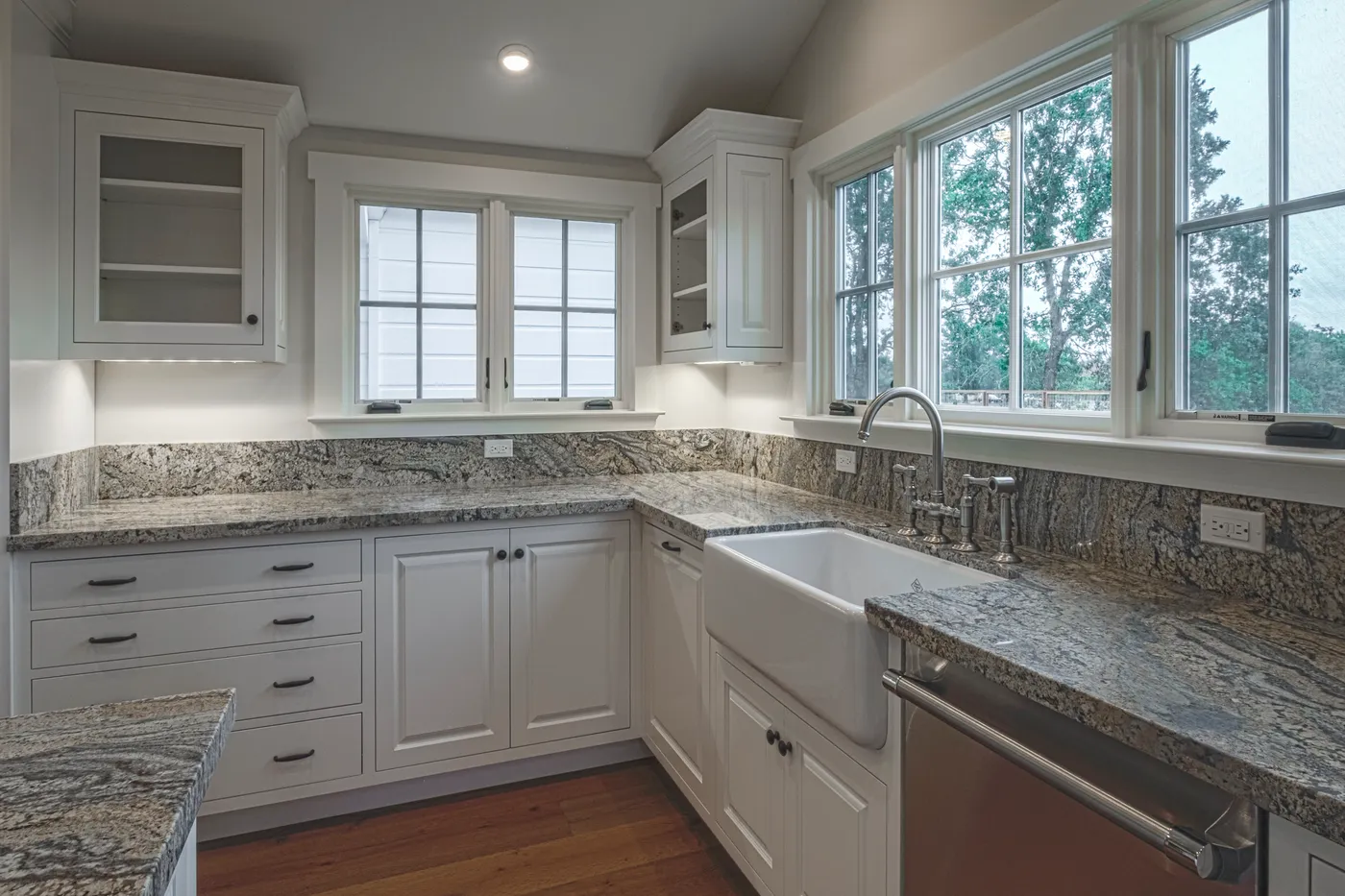 Corner run of cabinetry with a farmhouse sink below the windows
