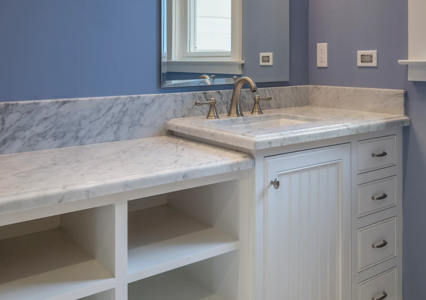 Guest vanity in marble with an open shelf alongside