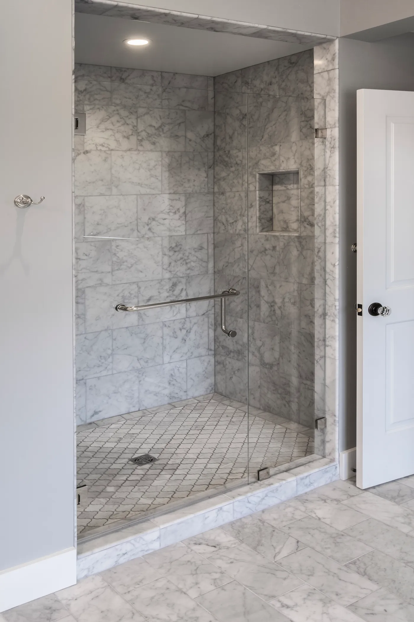 Marble shower behind a frameless glass door