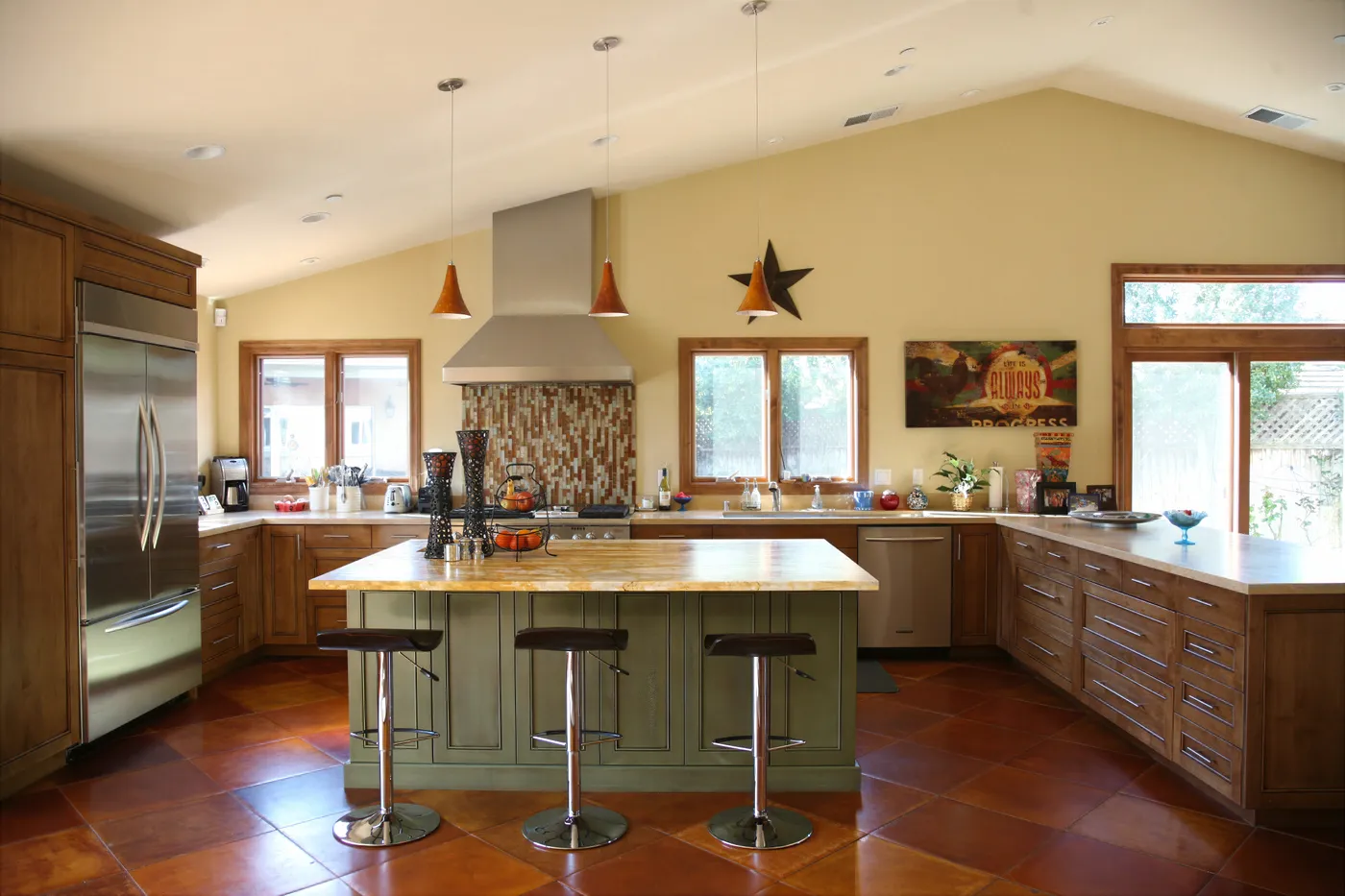 Kitchen under a vaulted ceiling, a green island below the stainless hood