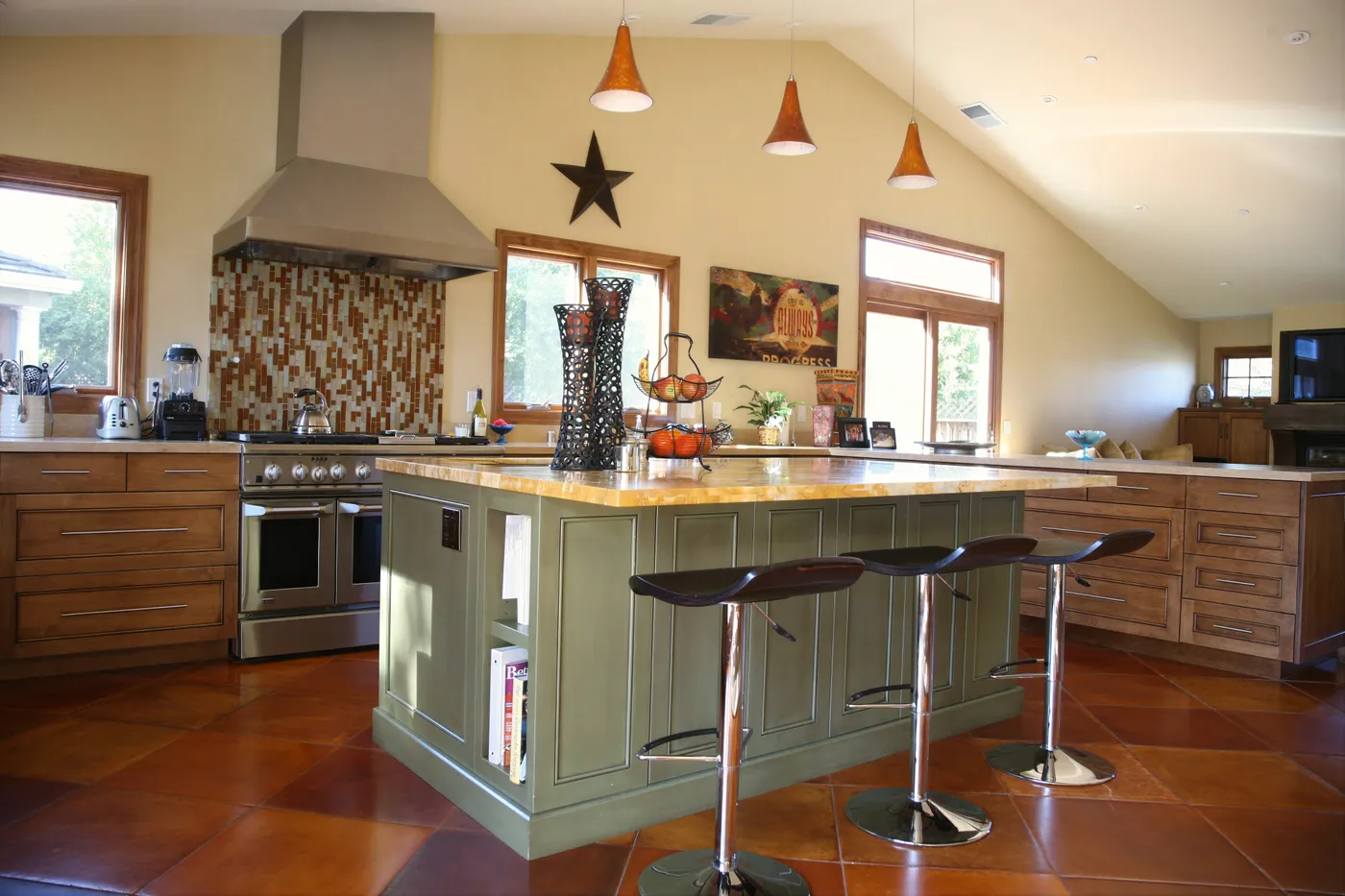 Green island with counter stools, the range and mosaic splashback behind