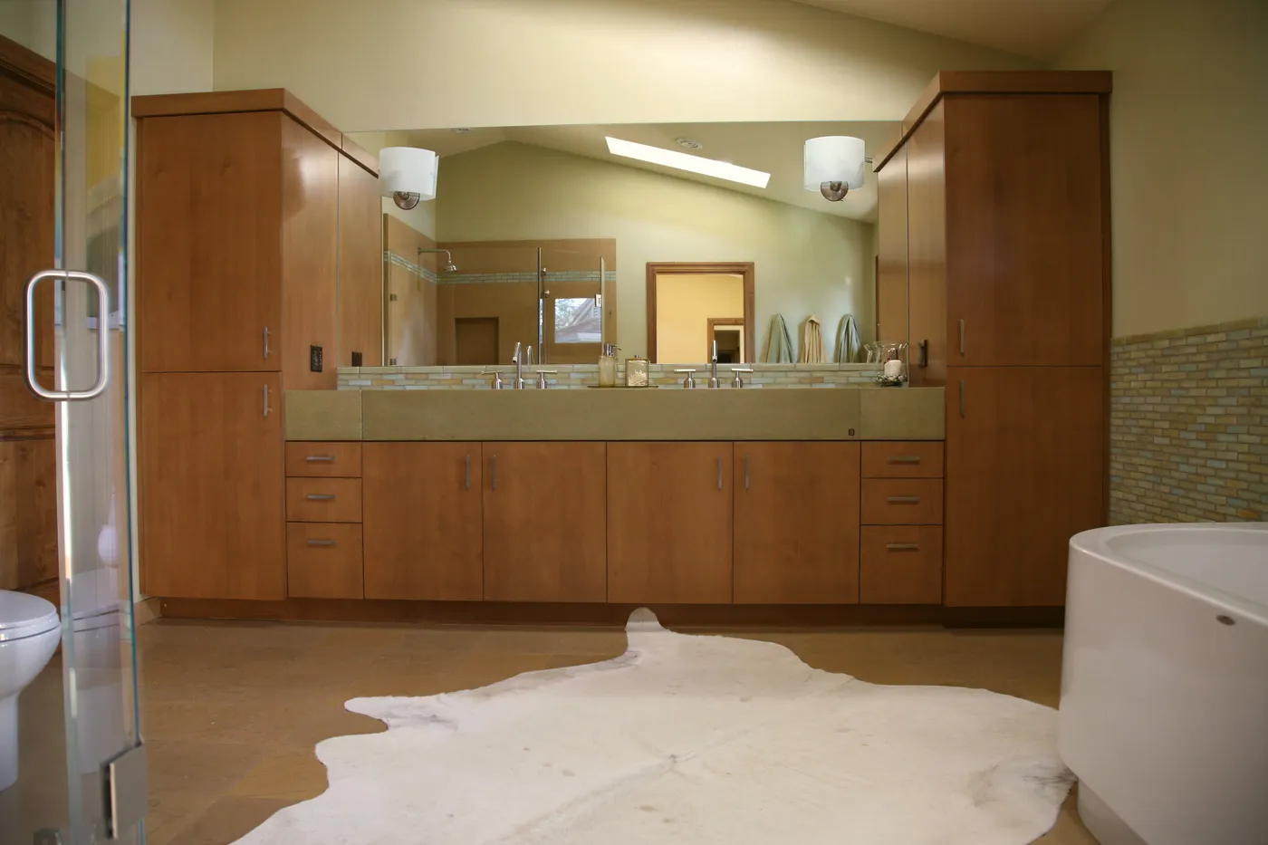The bath from the shower side, a hide rug on the floor beside the tub