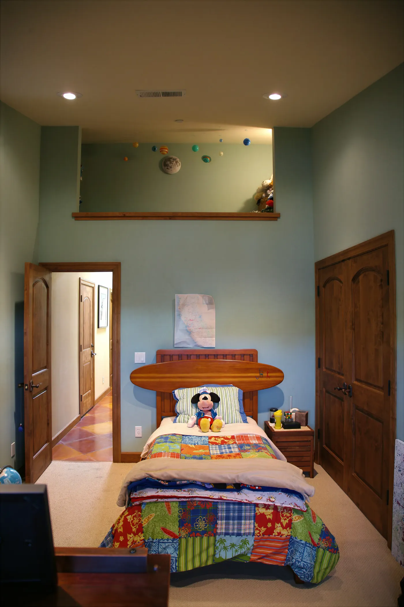Child's bedroom in green with a surfboard headboard and a high display shelf