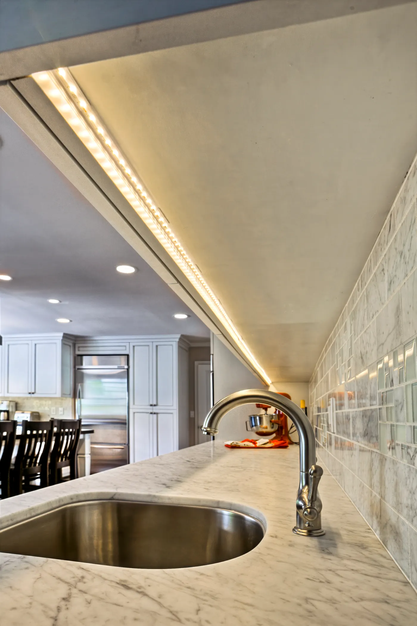 Prep sink in the marble counter, lit by a strip light under the upper cabinet