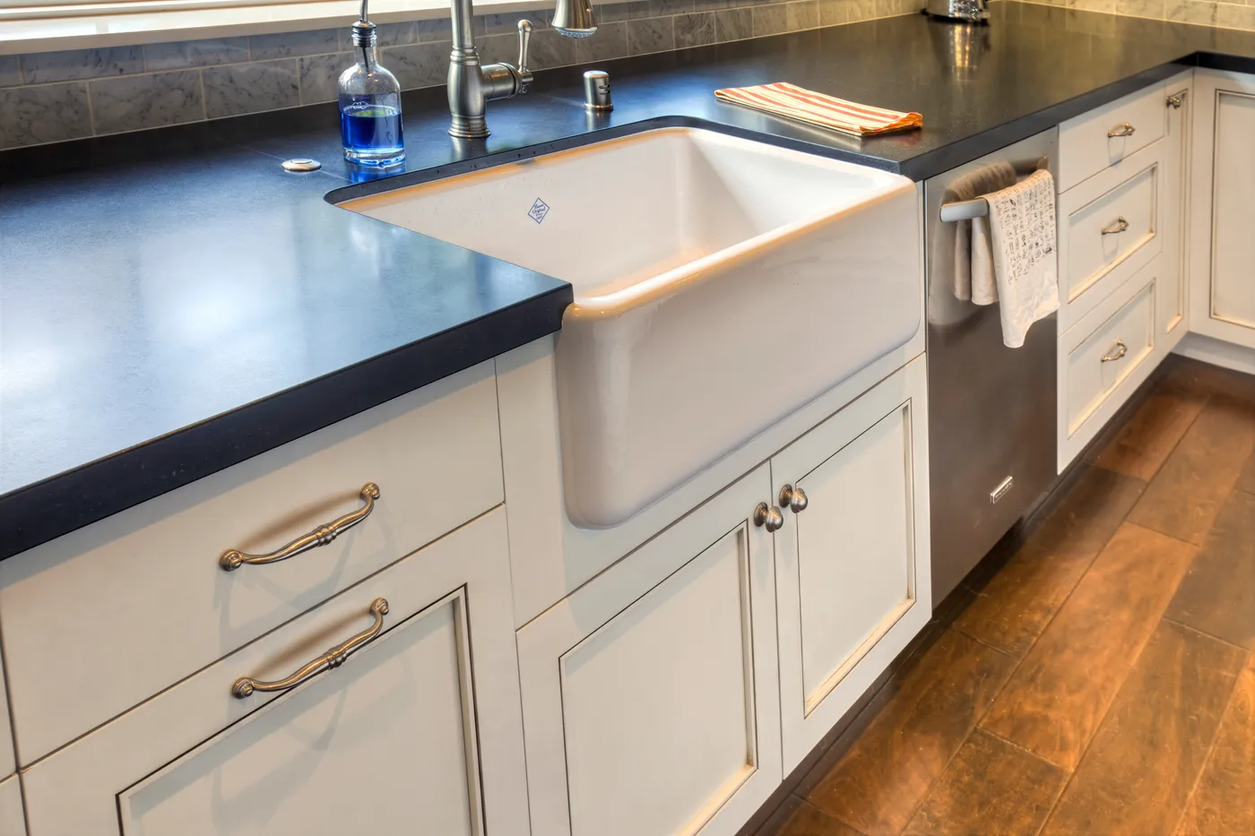 Farmhouse sink and dishwasher set into the honed black counter