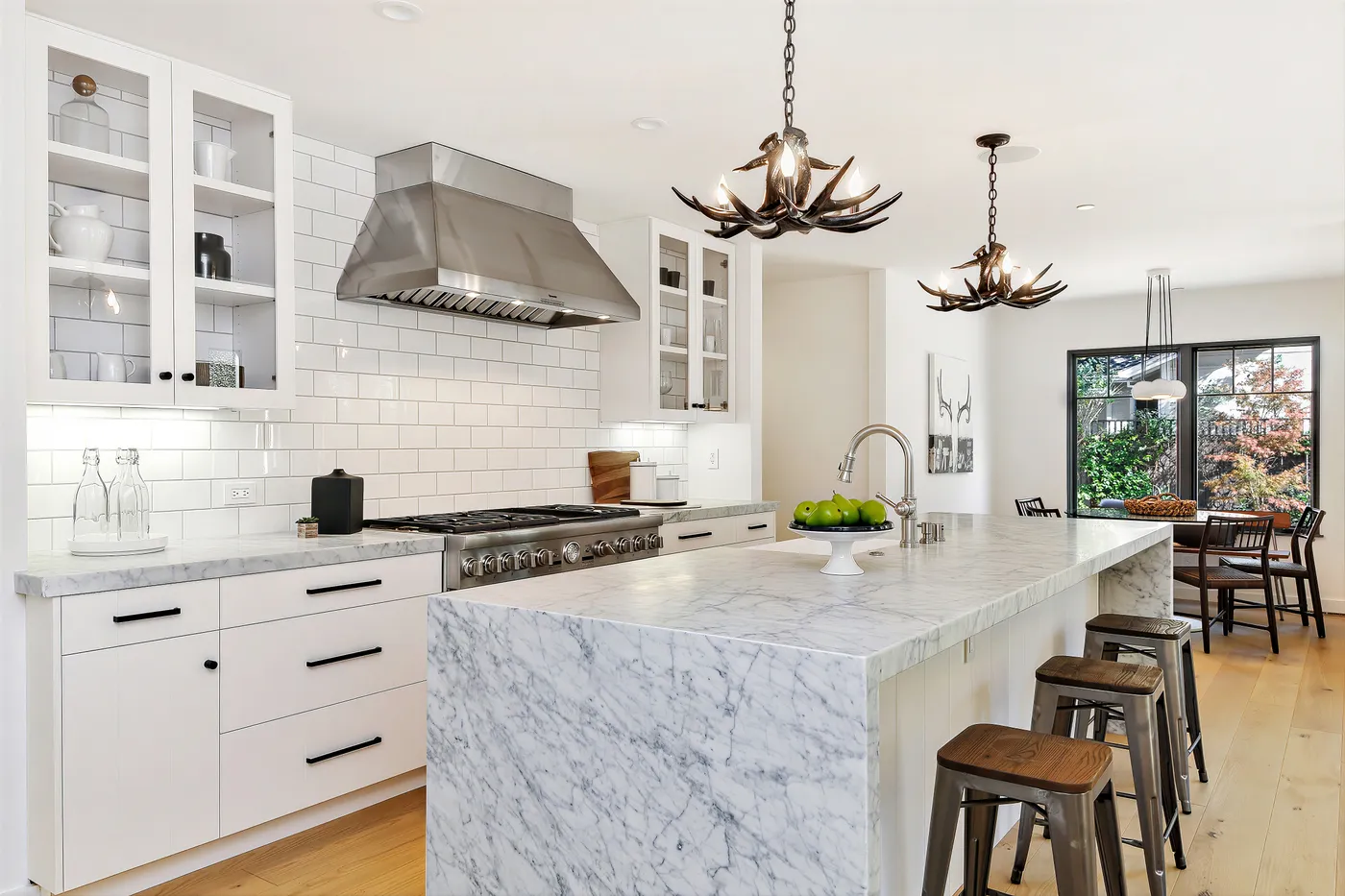 Kitchen with a stainless hood over the range and glazed upper cabinets either side