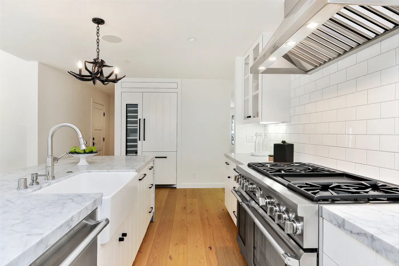 Farmhouse sink set into the marble island, the range and panelled refrigerator beyond