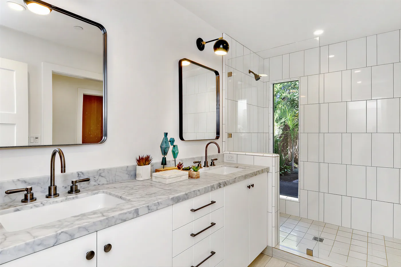 Bathroom with a marble double vanity and a walk-in shower in white tile