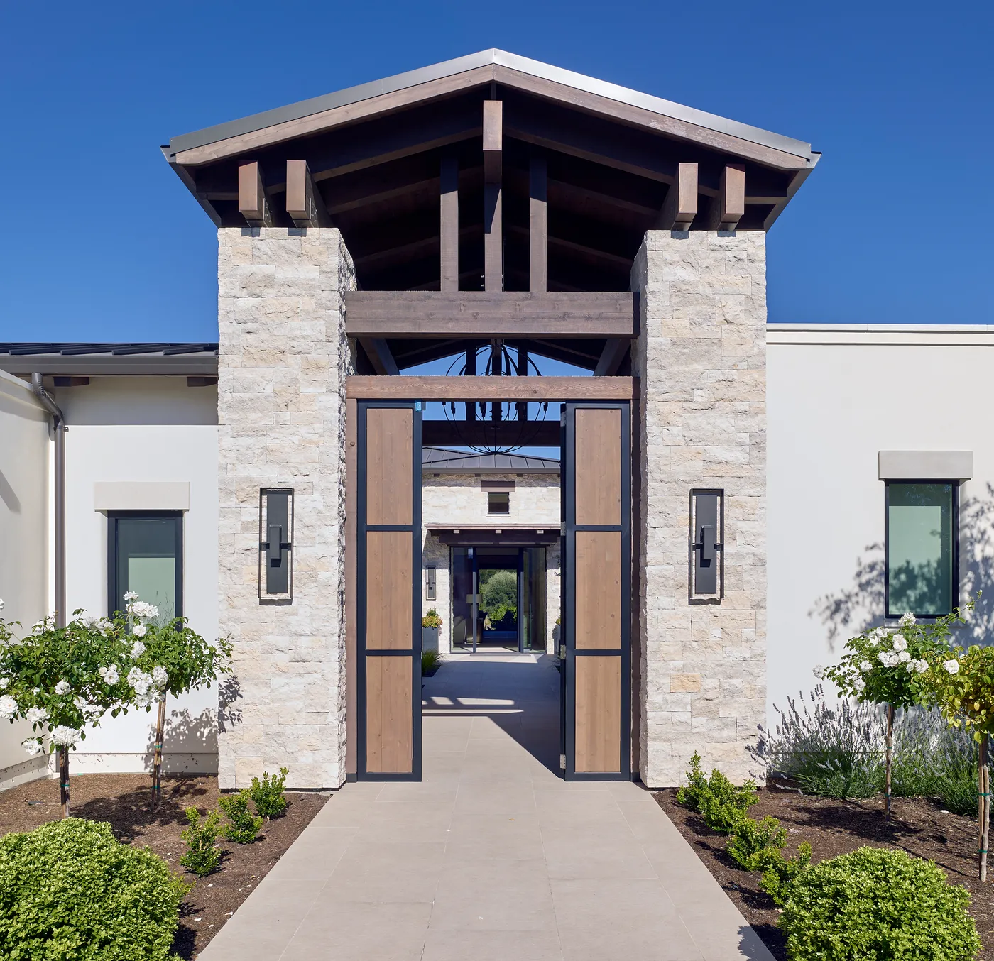 Front entry with stone piers and an exposed timber truss above the doors