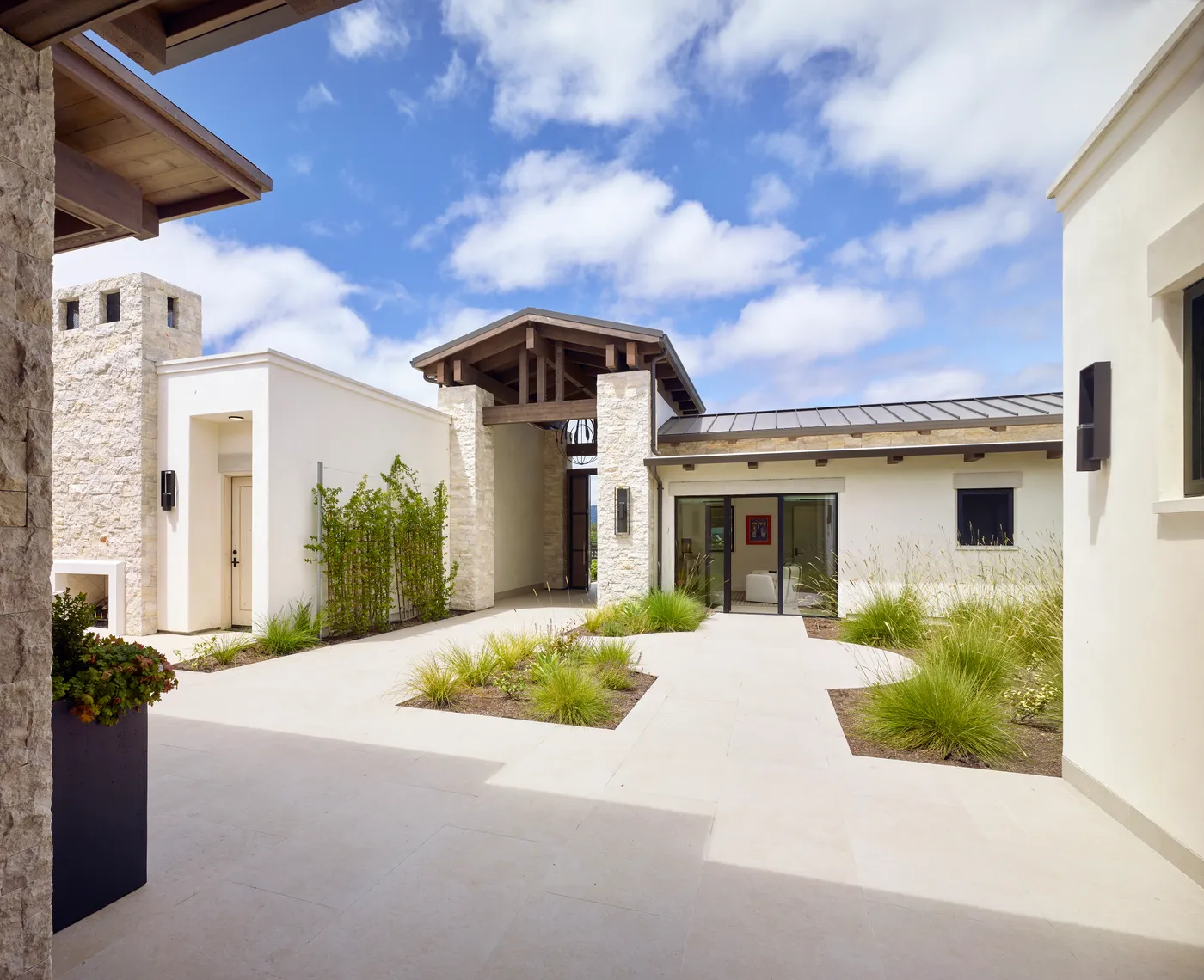 Entry courtyard with a stone tower and grasses planted into the paving