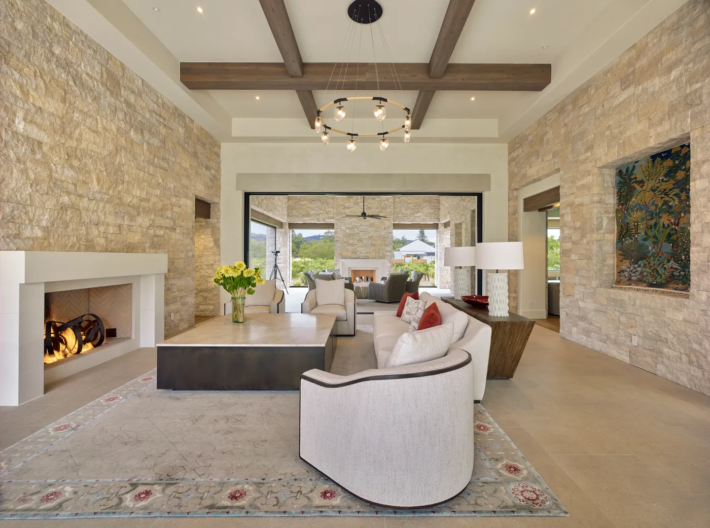 Living room with stone walls and timber beams, open to the terrace through sliding glass