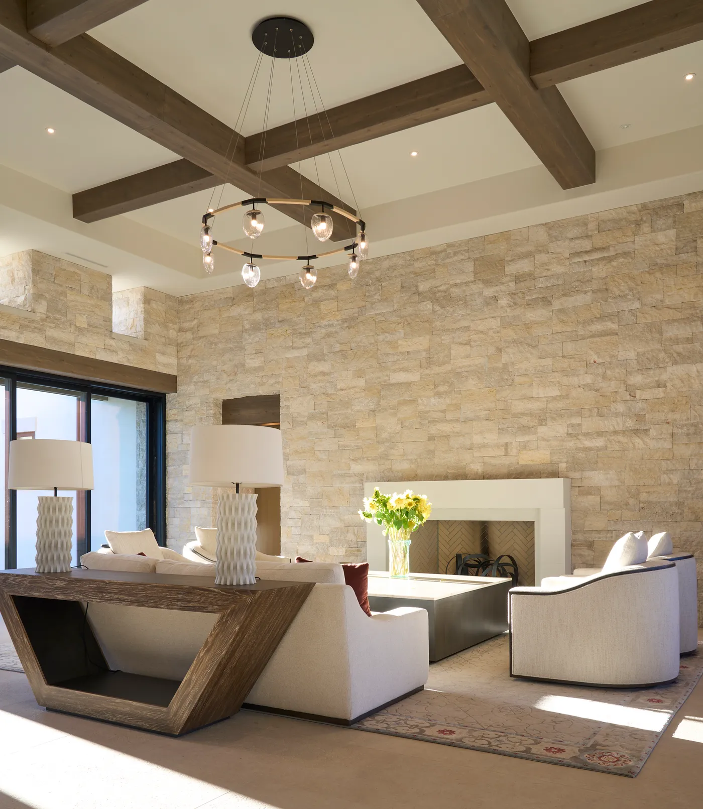 Living room fireplace set into the stone wall below a ring chandelier