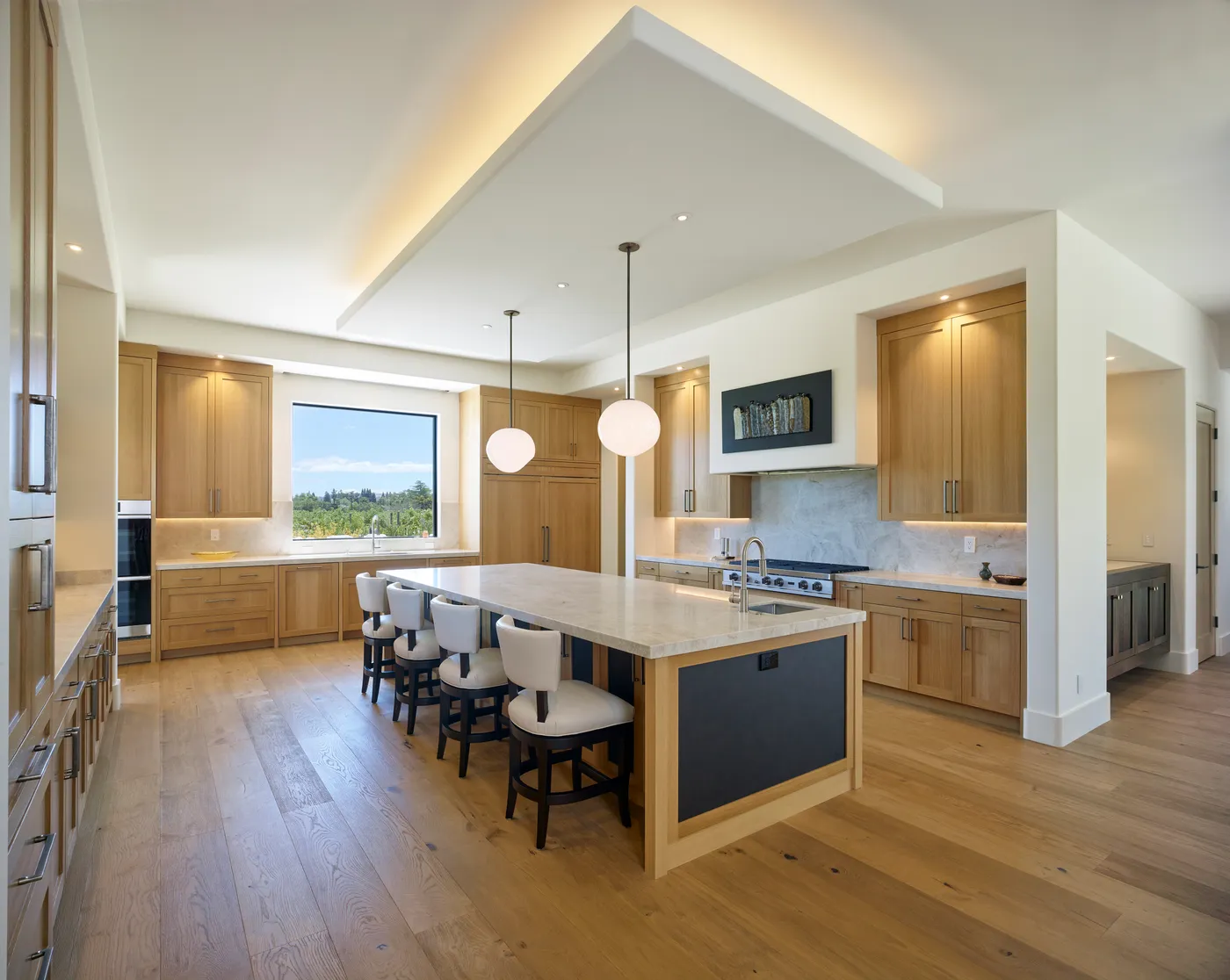 Kitchen with a long island, white oak cabinetry and a window above the sink