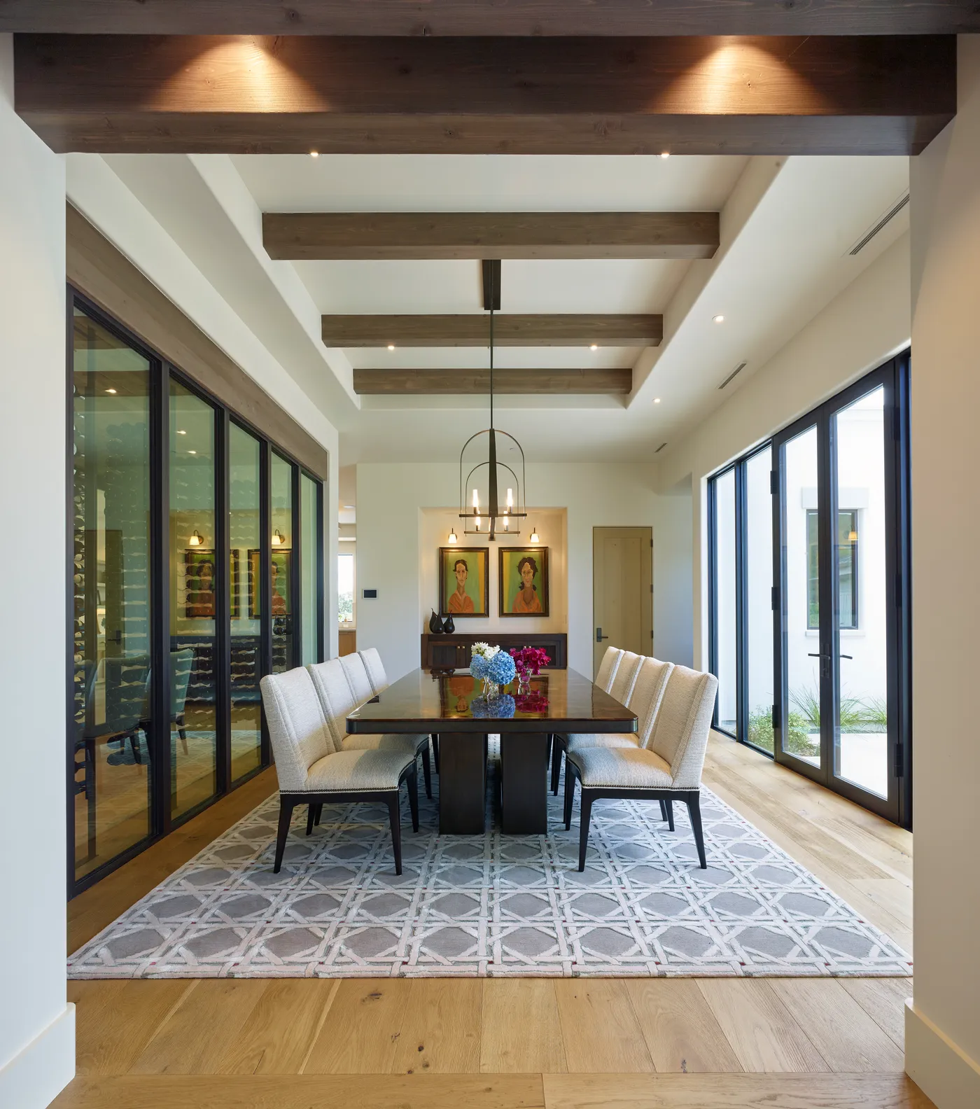 Dining room under timber beams between the glazed wine wall and doors to the courtyard