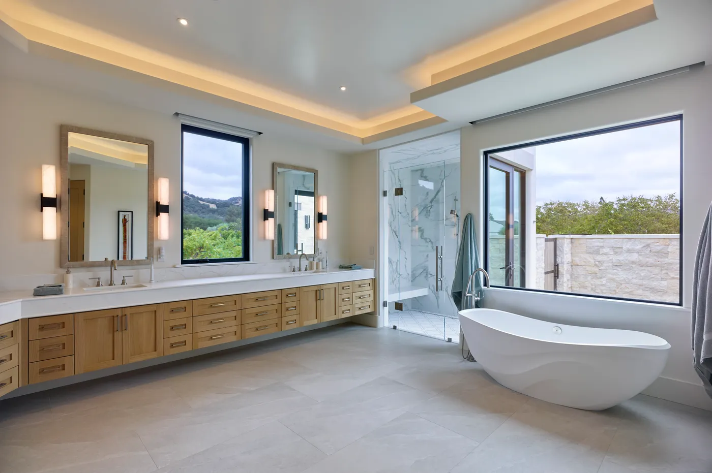 Primary bath with a double vanity, marble shower and freestanding tub